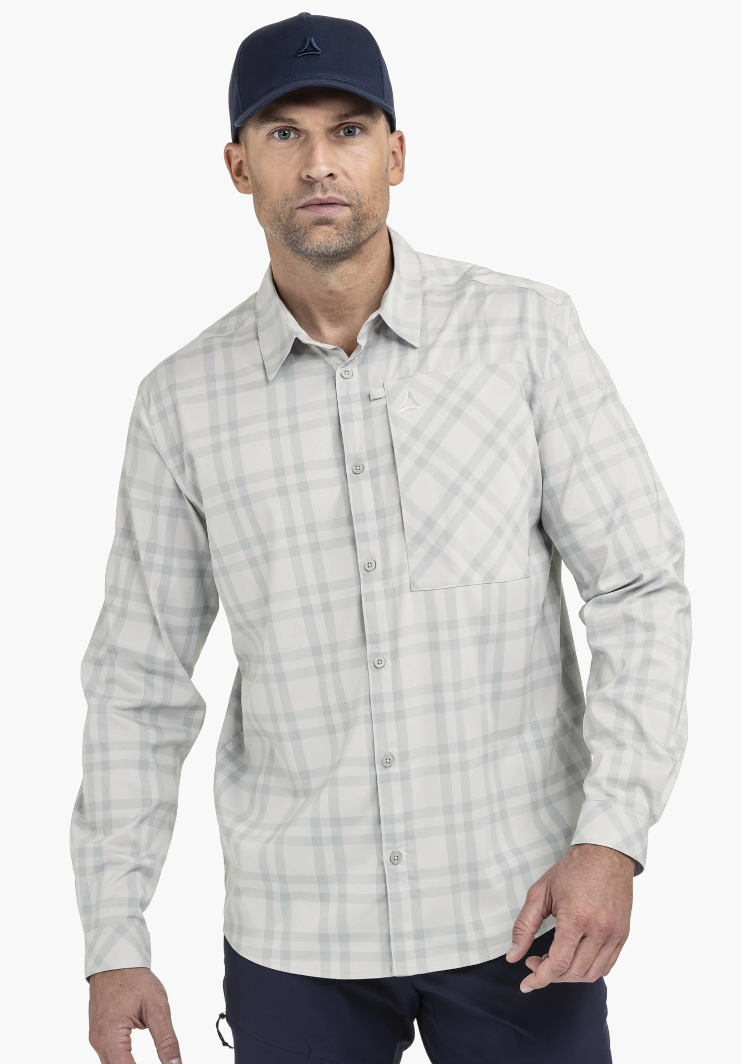 Shirt Style Fraris MEN est présenté dans un gris classique avec un motif à carreaux discret. Le modèle fait face à l'objectif devant un arrière-plan neutre. La poche poitrine est ornée du logo Schöffel élégant.
