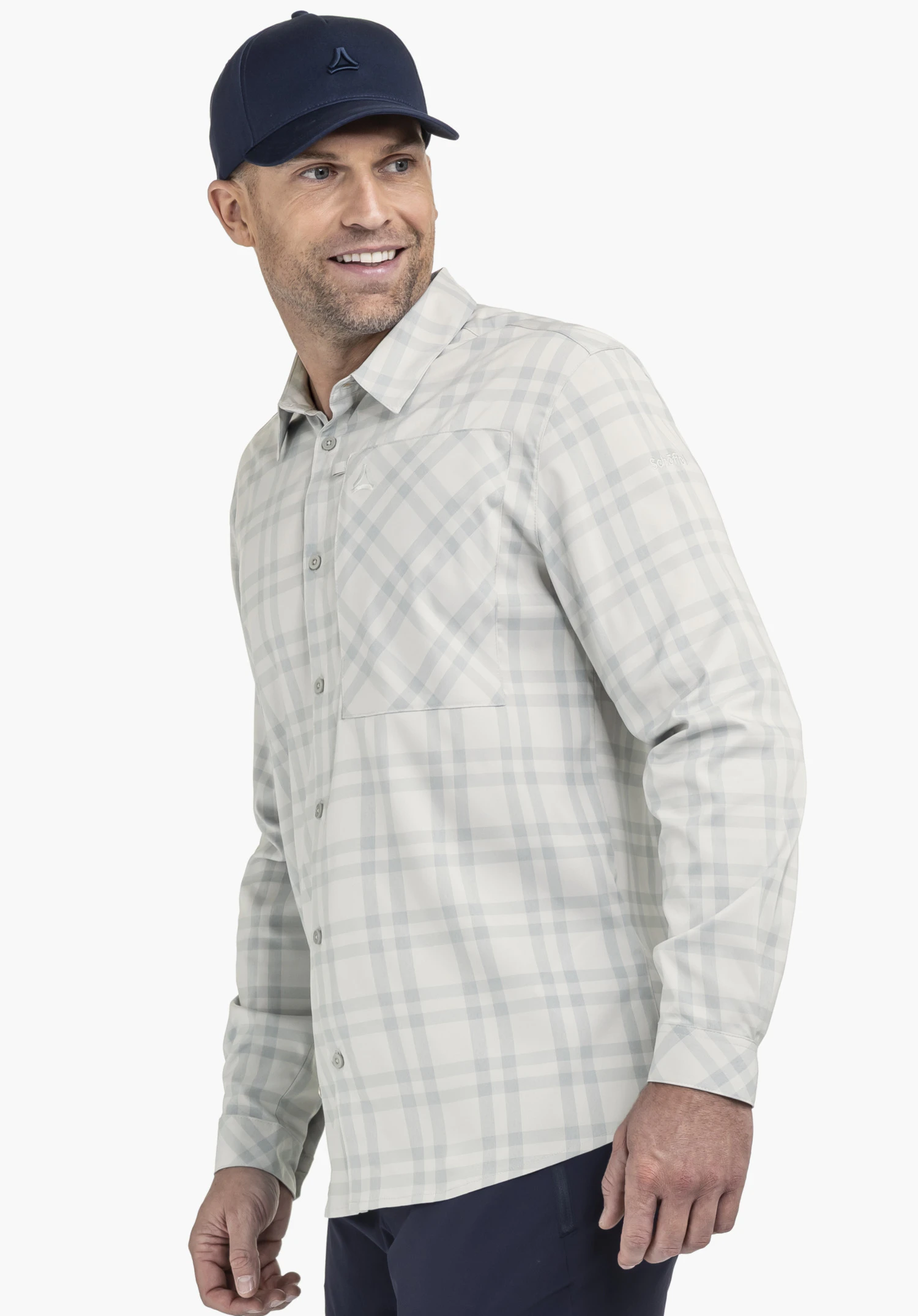 Shirt Style Fraris MEN en gris, porté par un mannequin souriant sur un fond neutre. Le mannequin adopte une pose de profil, mettant en valeur la chemise à manches longues avec le logo Schöffel discret sur la poitrine et le haut du bras.