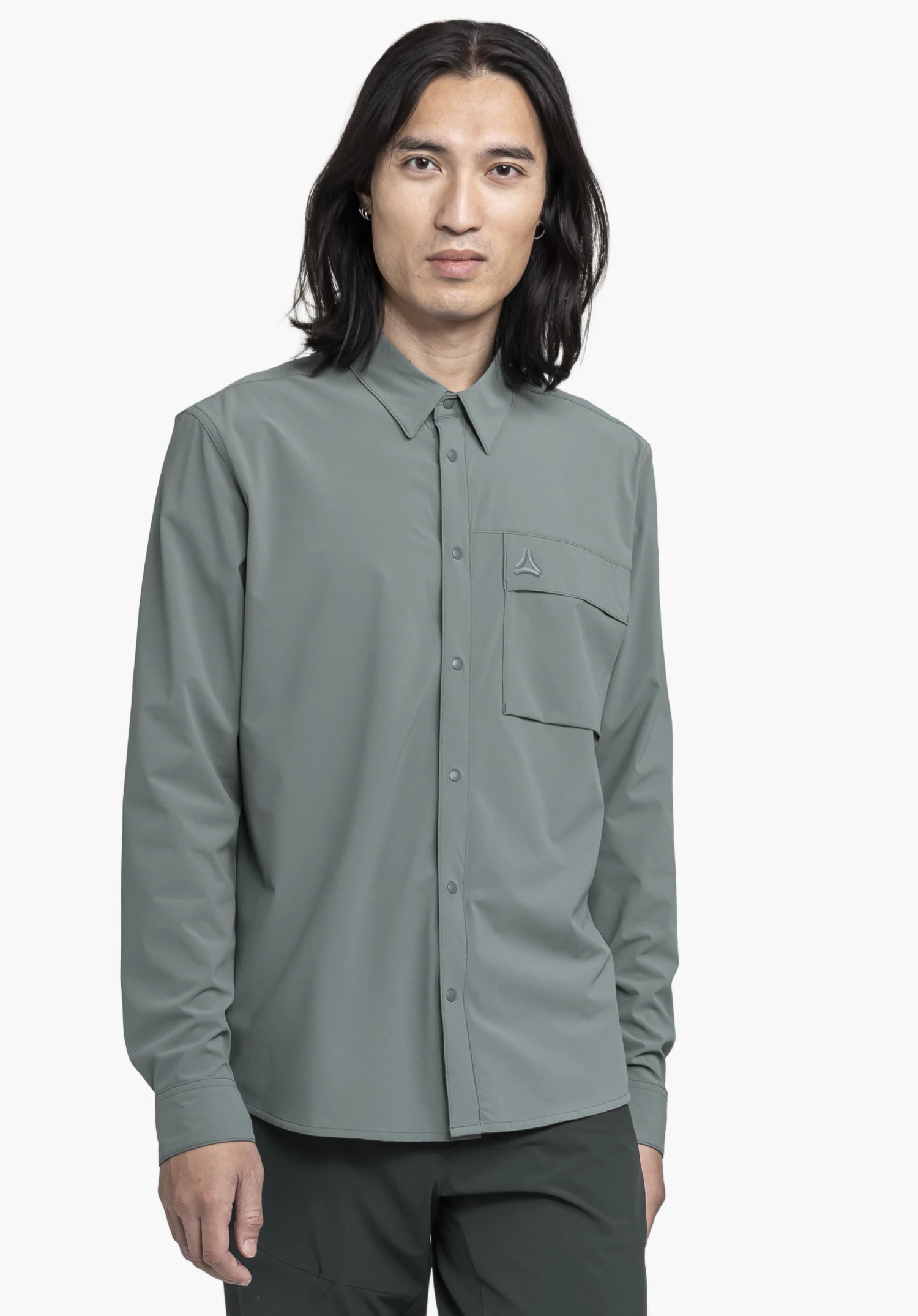 Shirt Style Dunajec MEN in grey. A model stands facing the camera against a neutral background, showcasing the long-sleeved shirt with a subtle chest pocket featuring the Schöffel logo in a matching tone.