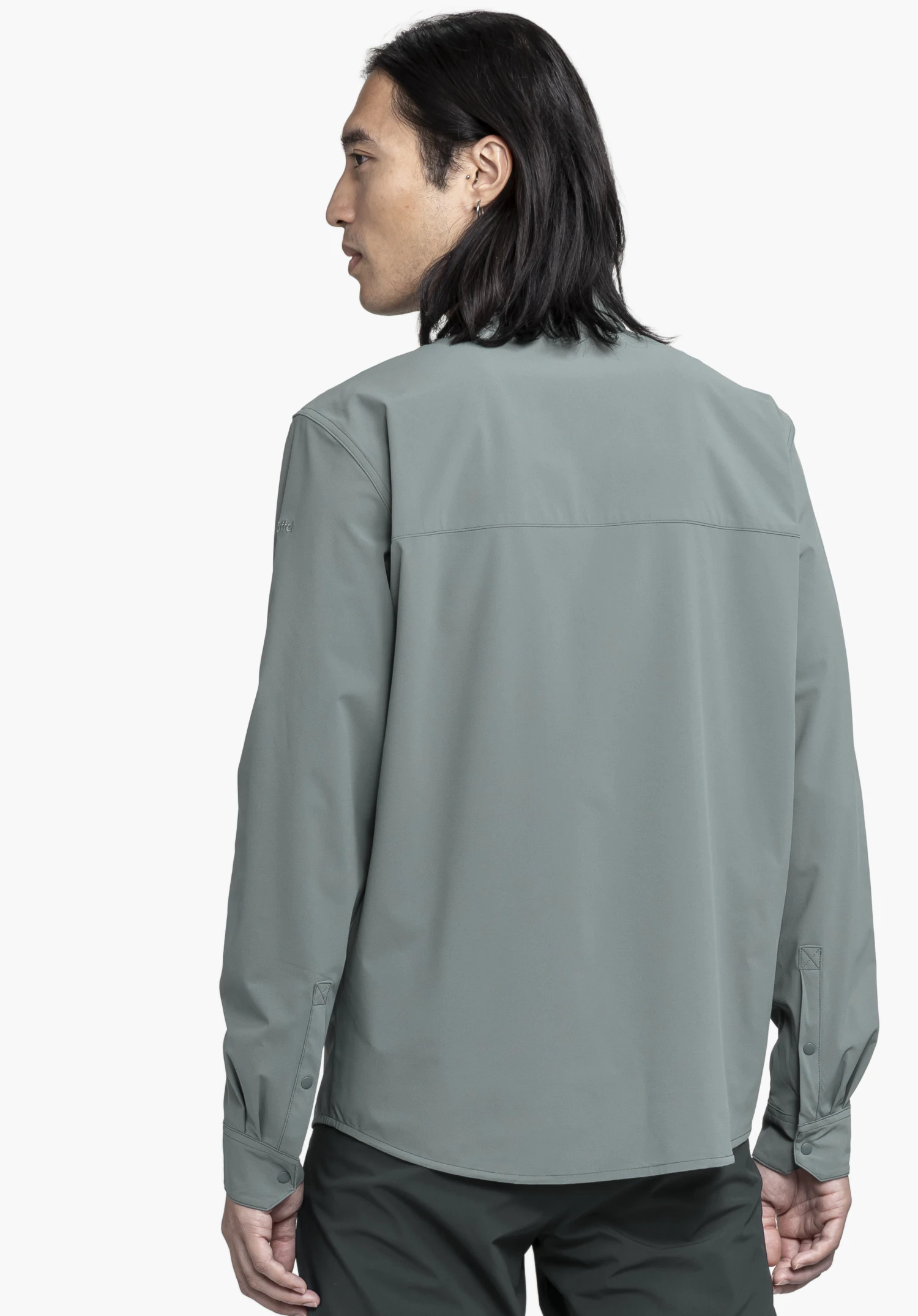 Shirt Style Dunajec MEN in grey is shown from a back view against a neutral background. The focus is on the clean lines, while the subtly embroidered Schöffel logo on the sleeve stands out as a high-quality detail.