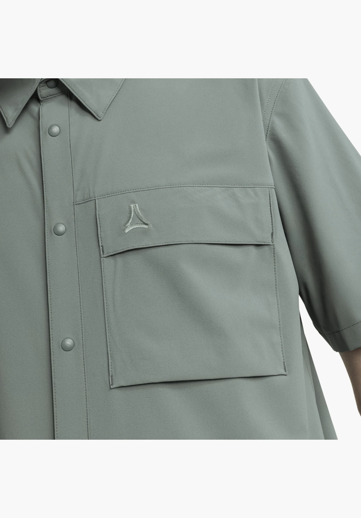 Shirt Style Dooser MEN shows a detail of the grey chest pocket with flap and embroidered Schöffel-Logo alongside the colour-matched press stud placket, close-up against a white/neutral background.