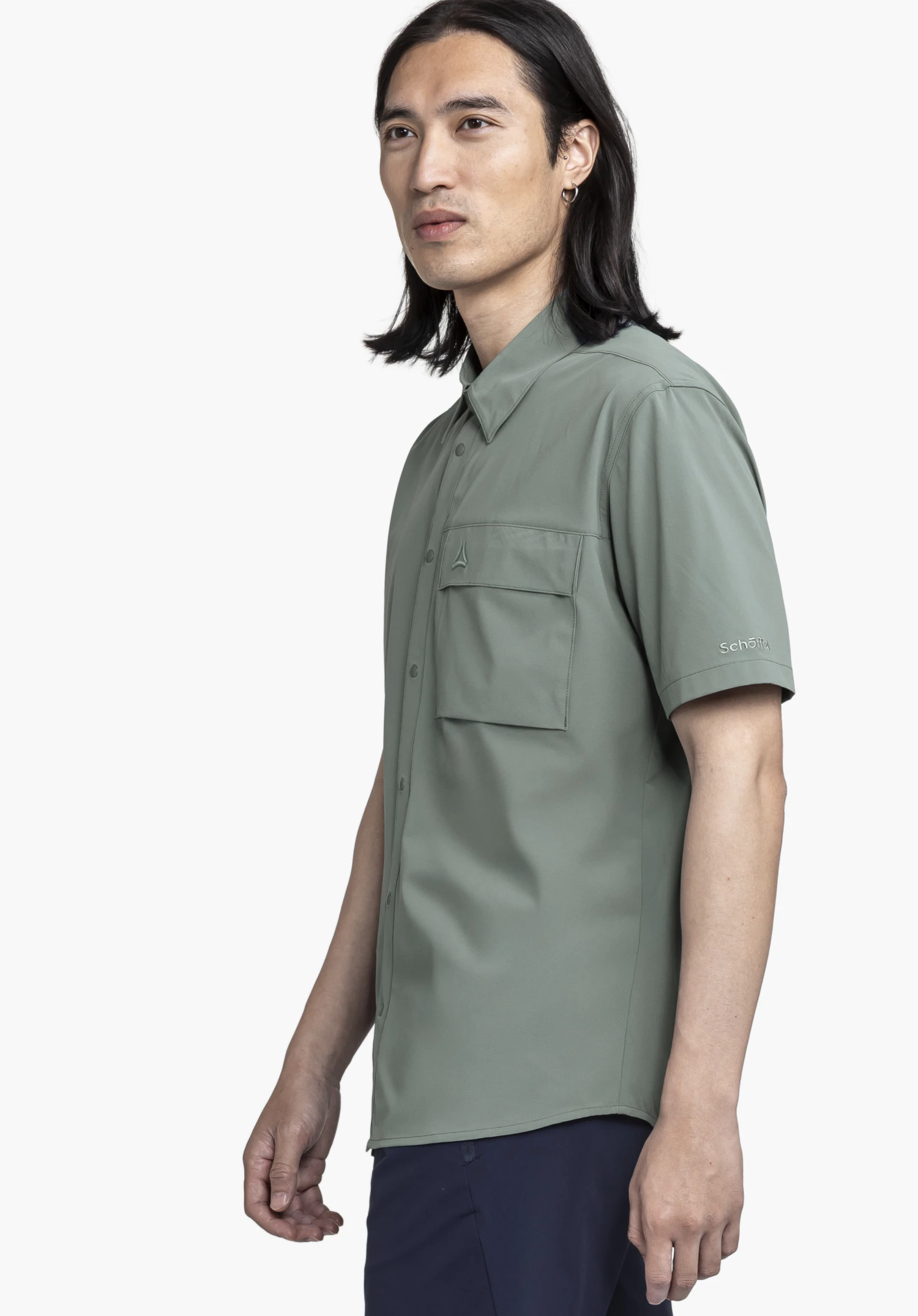 Shirt Style Dooser MEN in grey, worn by a model standing in a side profile pose. Set against a neutral background, the design highlights the subtle Schöffel logo on the sleeve and the functional chest pocket.
