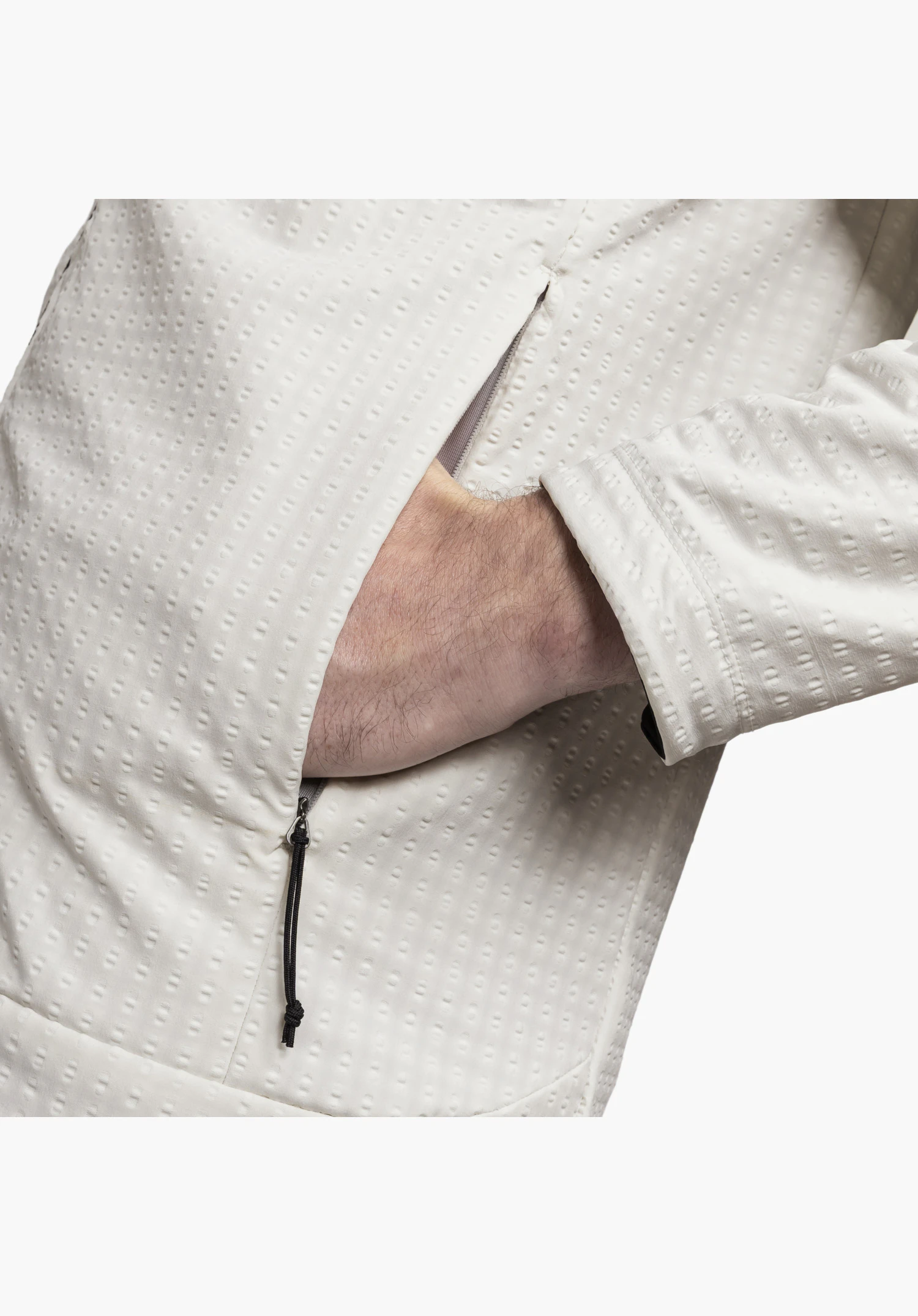 Fleece Hoody Style Enixa MEN, focusing on the textured fleece fabric in the colour natural with its distinct three-dimensional pattern and a hand in the zipped side pocket featuring a black cord puller, close-up against a white/neutral background.