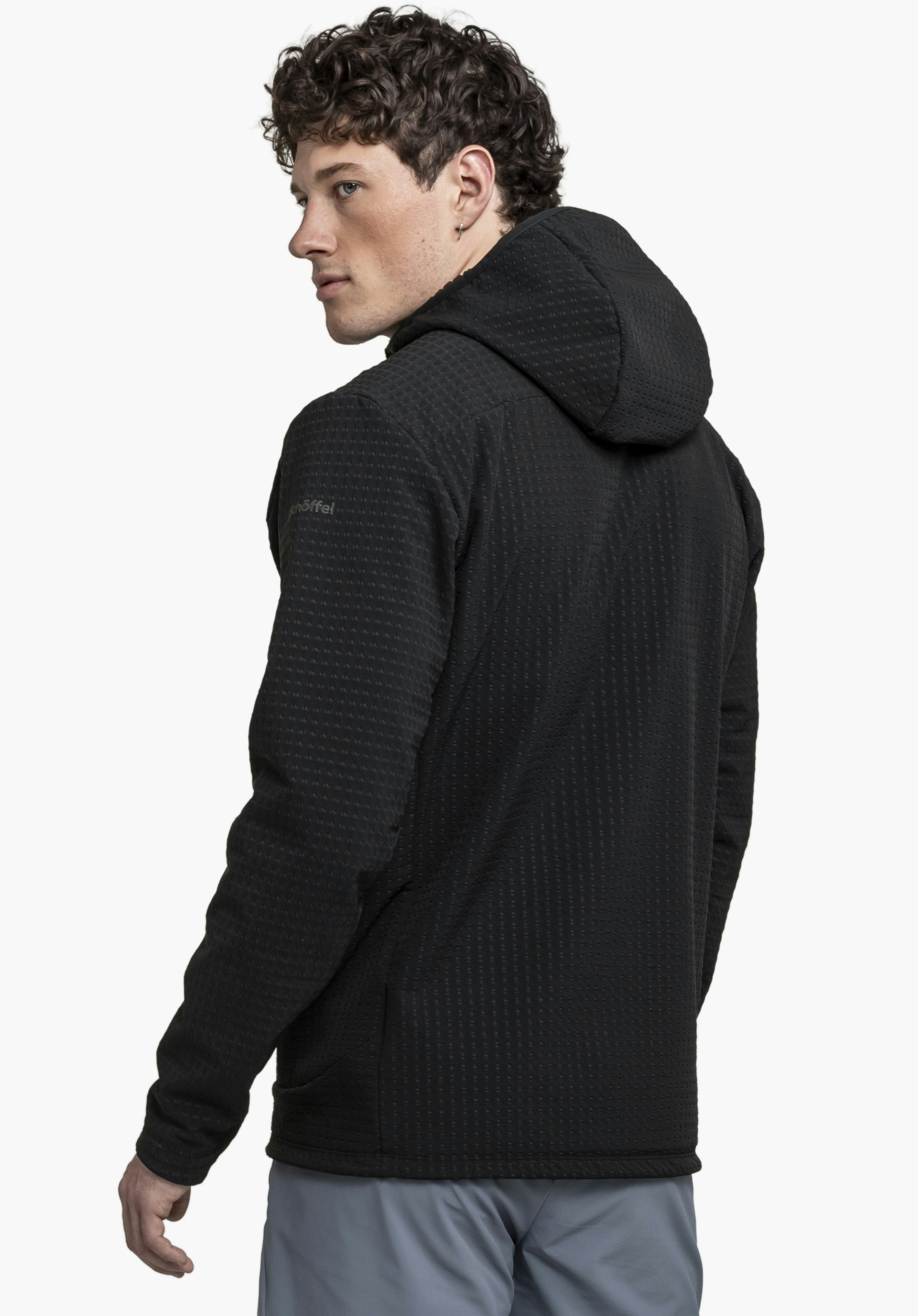 Fleece Hoody Style Enixa MEN in black, rear view on a model looking over his shoulder, with the Schöffel logo visible on the sleeve against a neutral background.