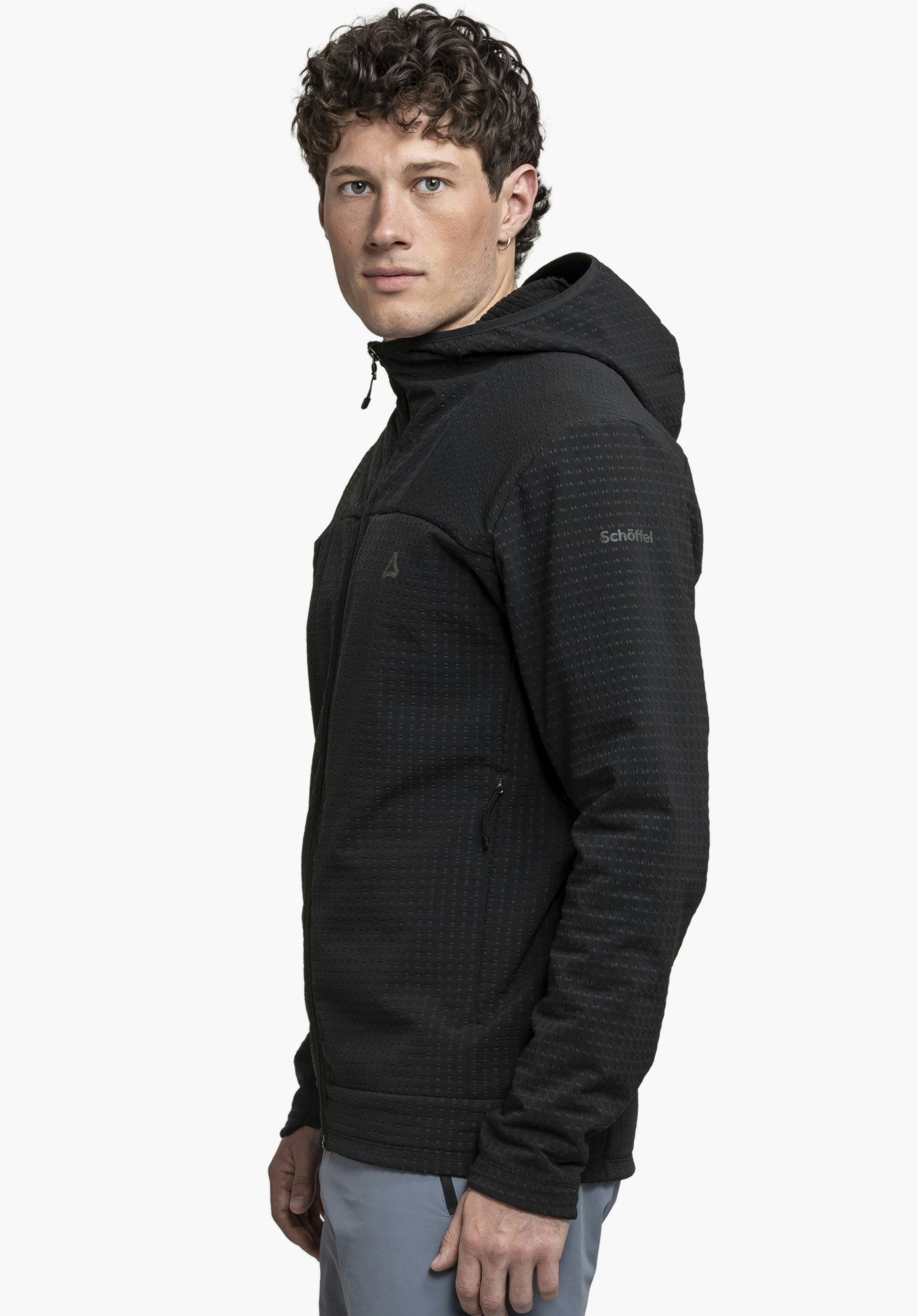 Fleece Hoody Style Enixa MEN: A model is standing in a side profile view against a neutral background, wearing the black hoody. The subtly placed Schöffel logo on the upper arm highlights the functional design.