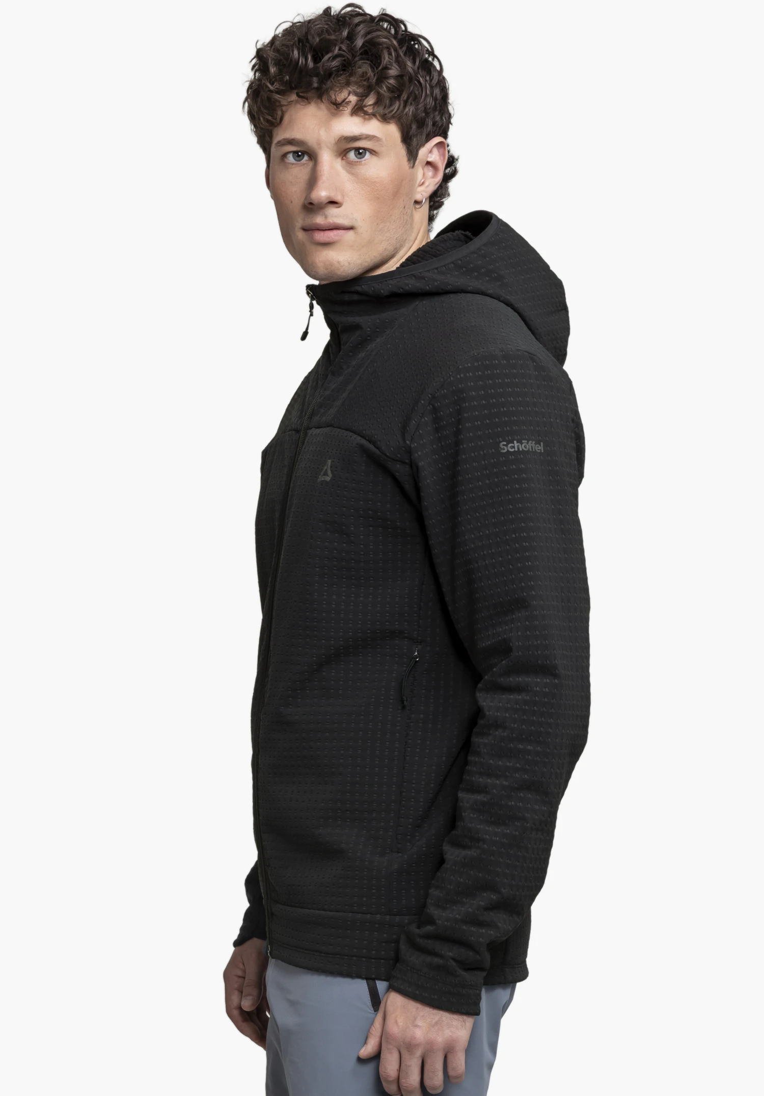 Fleece Hoody Style Enixa MEN: A model is standing in a side profile view against a neutral background, wearing the black hoody. The subtly placed Schöffel logo on the upper arm highlights the functional design.