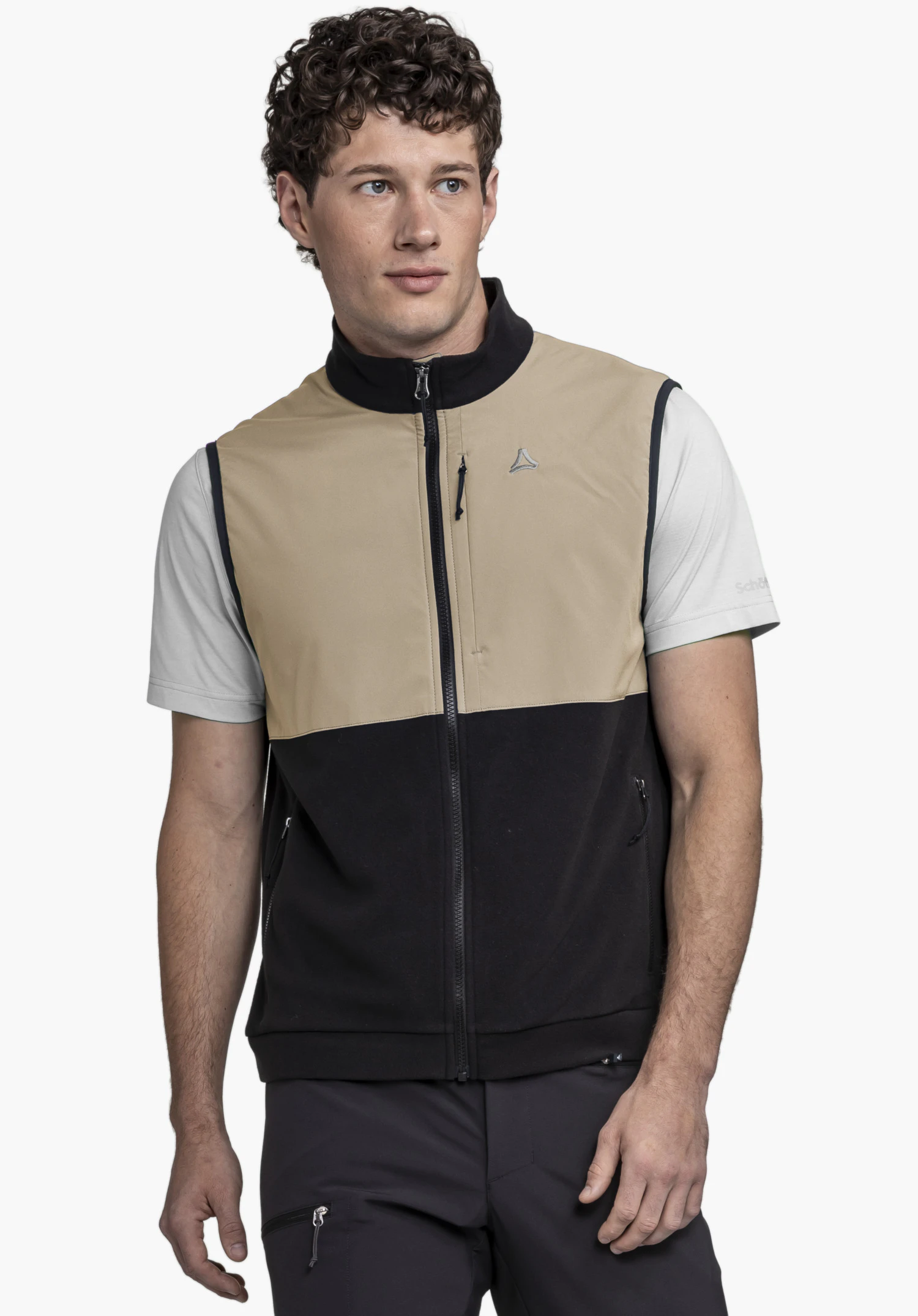 Fleece Vt Style Ash MEN on a model. The man stands facing forward, looking slightly to the side, wearing the two-tone gilet which is black on the lower half. The Schöffel logo is visible on the left chest. Presented against a neutral background.
