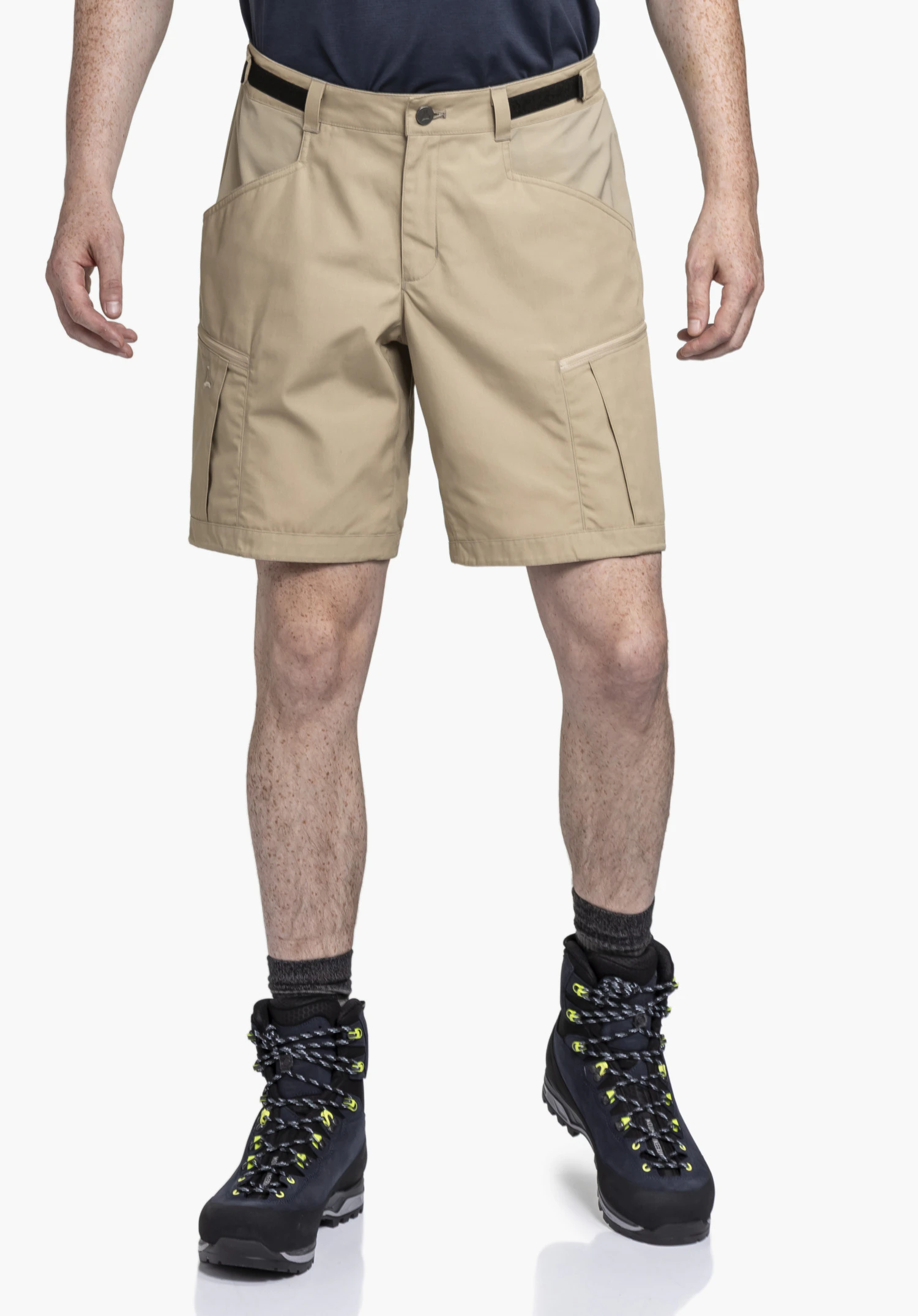 Shorts Style Maghera MEN in Beige. Ein Model steht frontal und präsentiert die kurze Hose mit praktischen Beintaschen und einem dezenten Schöffel-Logo. Aufgenommen vor einem neutralen Hintergrund, ideal für das nächste Outdoor-Abenteuer.