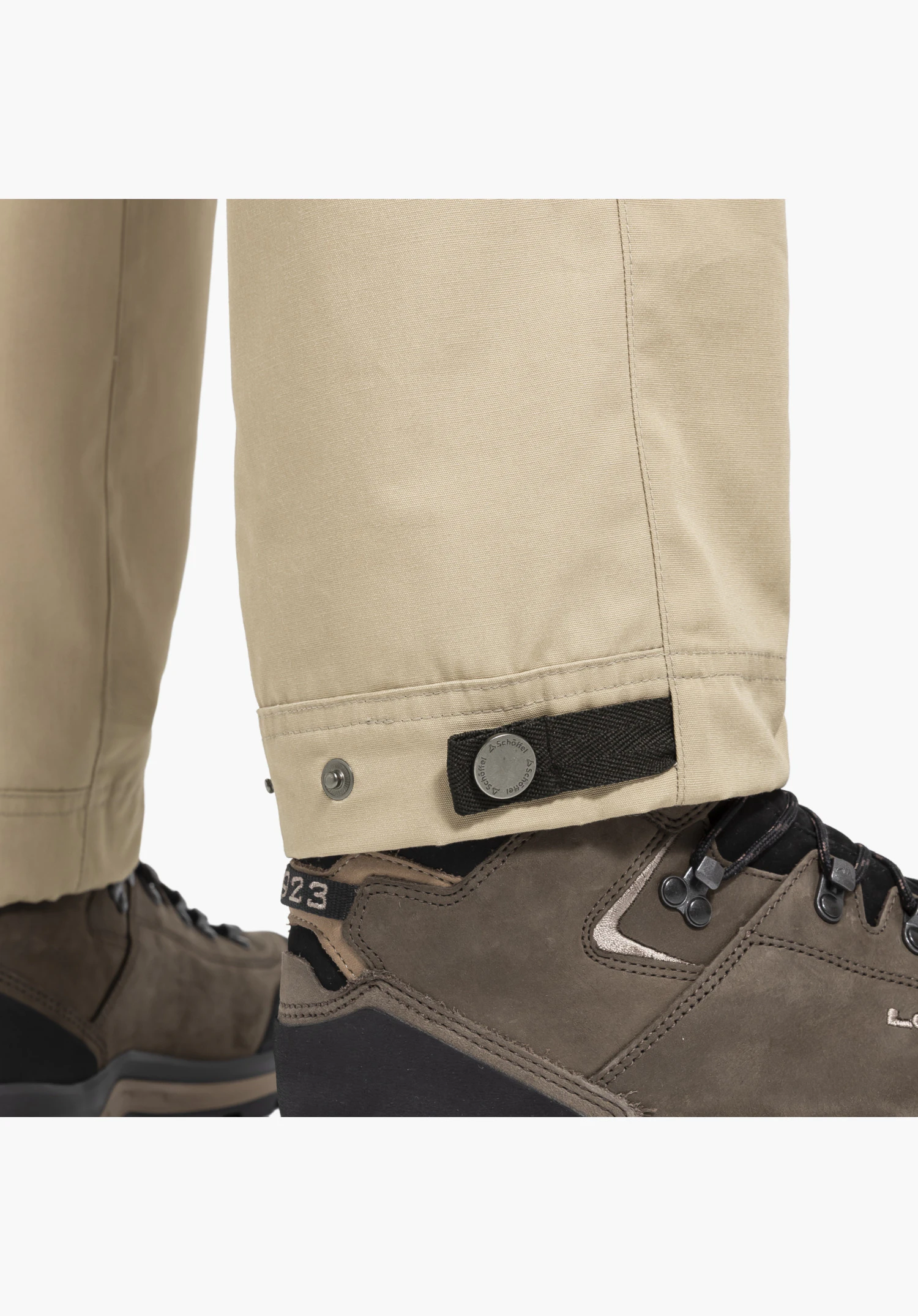 Pants Style Maghera MEN, view of the beige adjustable leg hem with a black strap and a metal popper featuring the Schöffel logo, close-up against a neutral background.