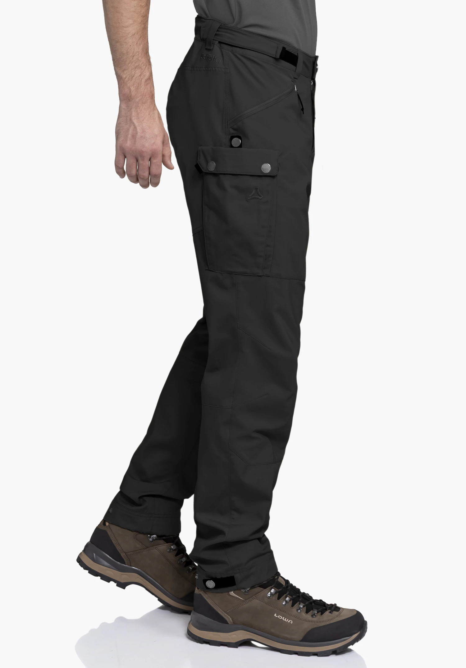 Pants Style Maghera MEN in black. The model is standing sideways against a neutral background, showcasing the functional fit of the hiking trousers. The subtle placement of the Schöffel logo highlights the premium look.