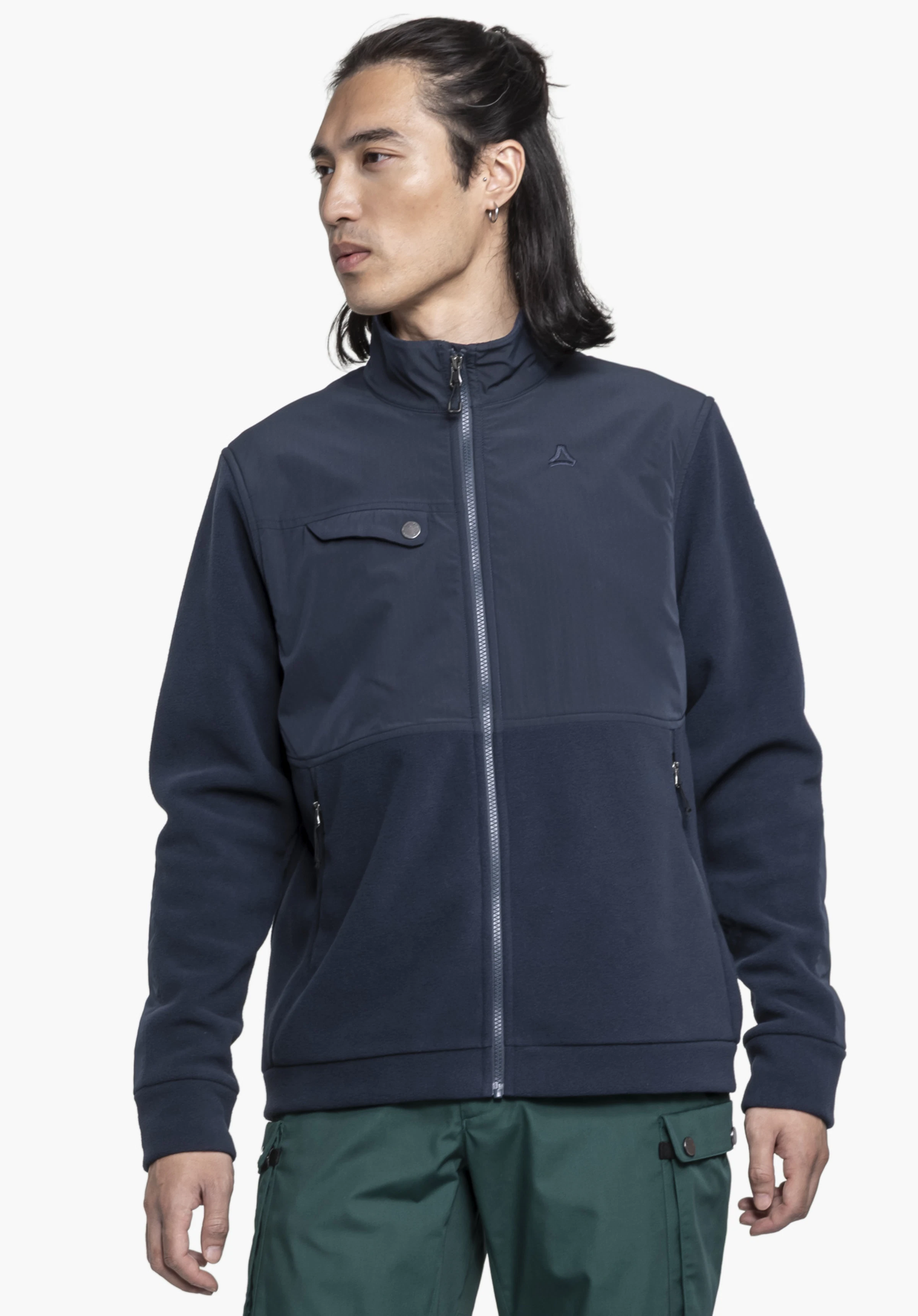 Fleece Jk Style Maghera MEN. A model stands facing the front, looking to the side, and presents the blue fleece jacket with a visible Schöffel logo on the chest against a neutral background.