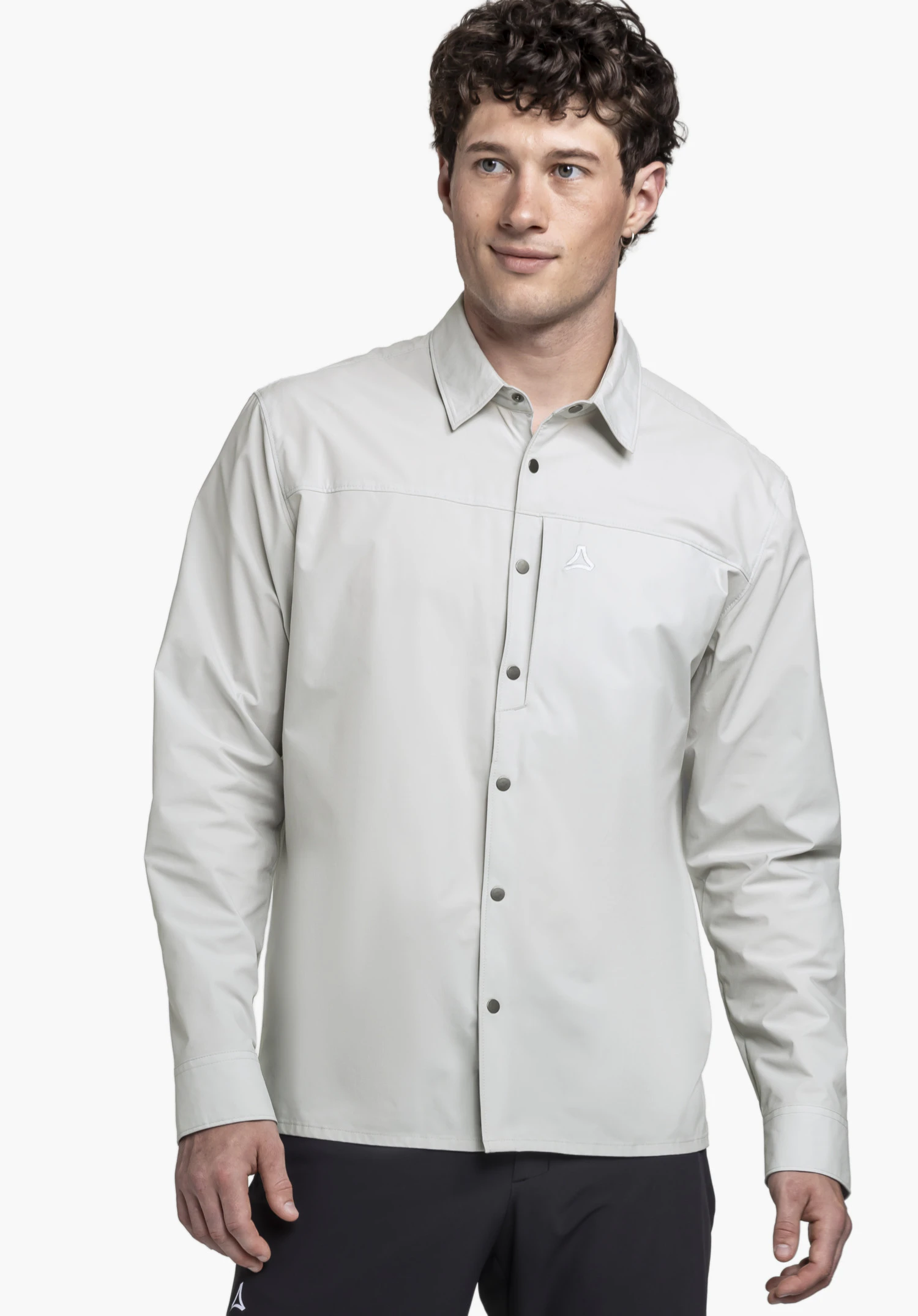 Shirt Style Maghera MEN an einem Model, das frontal steht und das graue Hemd mit dem Schöffel-Logo auf der Brust präsentiert, vor einem neutralen Hintergrund.