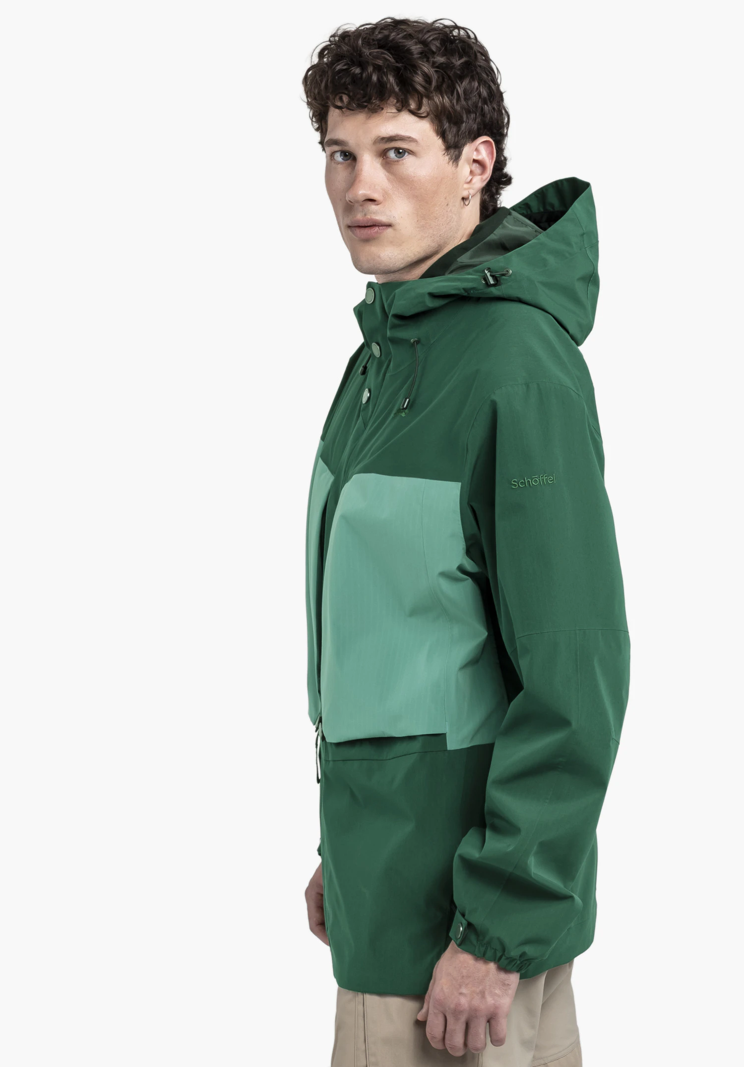 2L Jacket Style Maghera MEN in der Farbe Grün. Das Model steht seitlich vor einem neutralen Hintergrund und präsentiert die Jacke. Auf dem Oberarm ist das dezente Schöffel-Logo sichtbar.