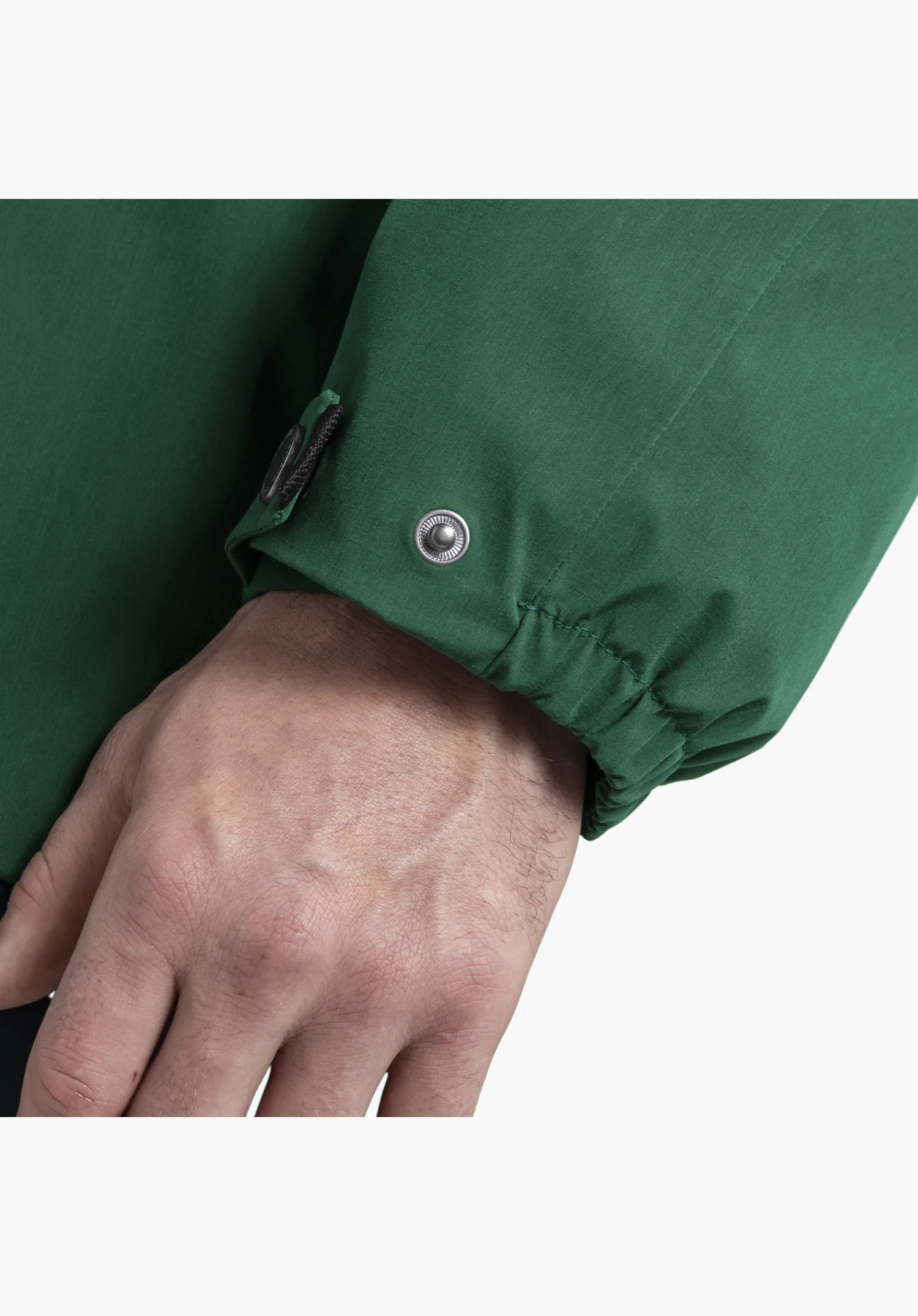 2L Jacket Style Maghera MEN. Der verstellbare Ärmelabschluss in Grün zeigt einen silbernen Metalldruckknopf und eine elastische Raffung, Nahaufnahme vor weißem/neutralem Hintergrund.