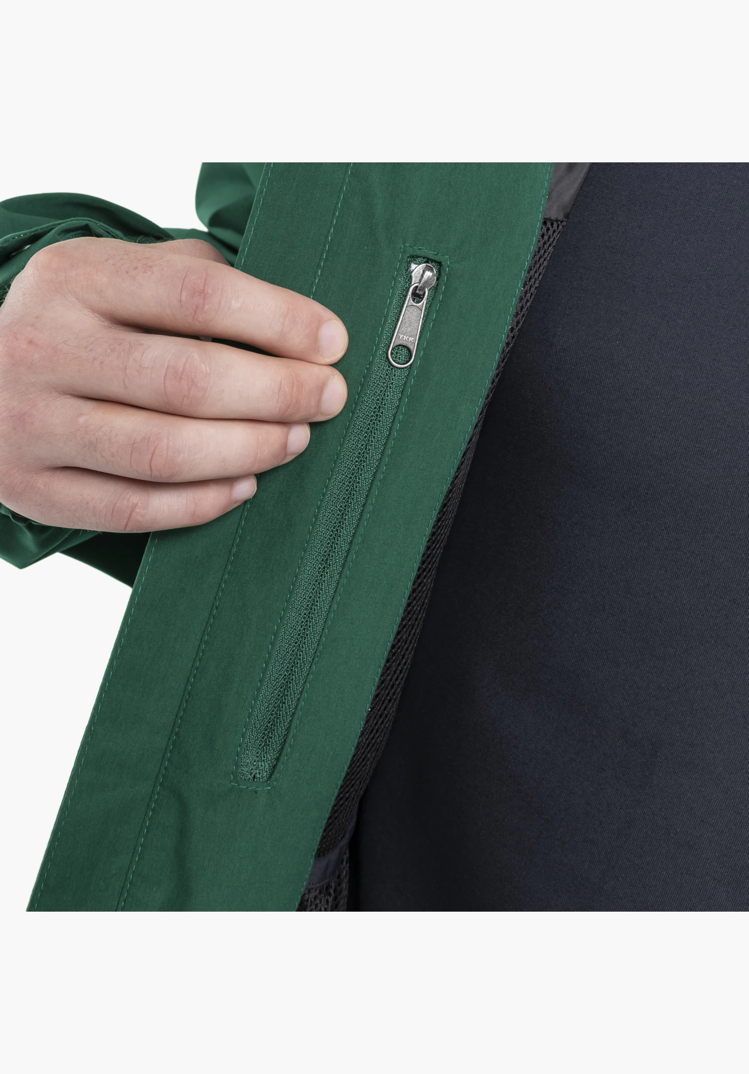 2L Jacket Style Maghera MEN zeigt das Detail einer verdeckten Innentasche mit grünem Reißverschluss und metallischem Schieber, die von einer Hand am grünen Stoff aufgeschlagen wird. Nahaufnahme vor weißem/neutralem Hintergrund.