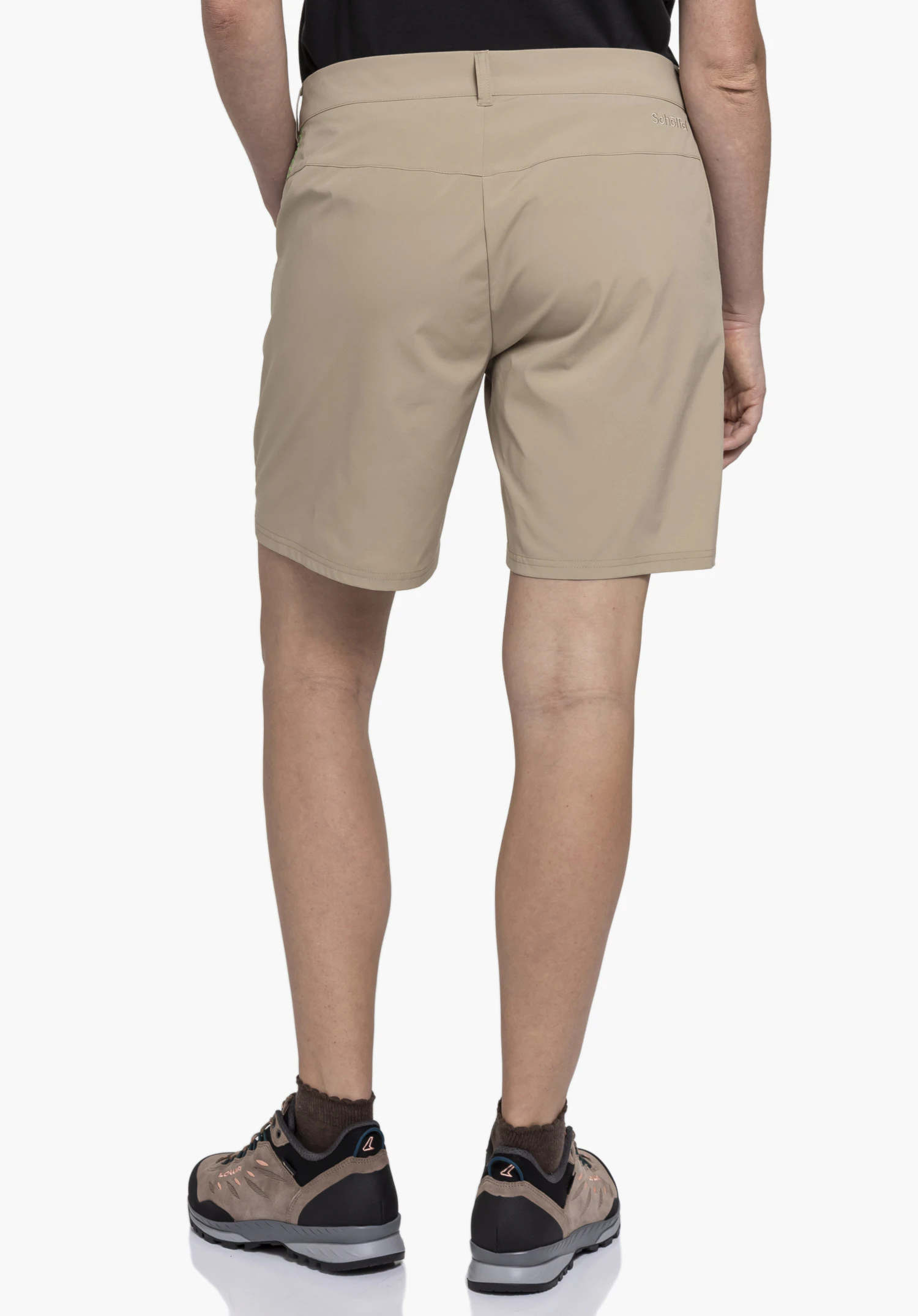 CIRC Shorts Style Smue WMN, getragen von einem Model in der Rückenansicht. Zu sehen ist die beige Hose mit Gürtelschlaufen und dem Schöffel-Logo auf der rechten Rückseite. Das Model steht aufrecht vor einem neutralen Hintergrund.