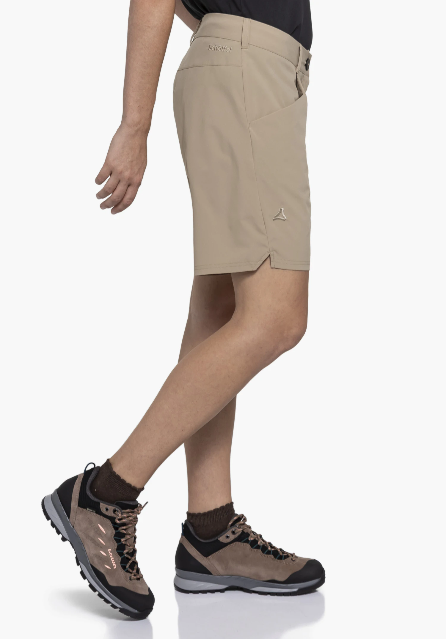 CIRC Shorts Style Smue WMN an einem Model, das in einer Schrittbewegung seitlich steht. Die beigefarbene kurze Hose mit sichtbarem Schöffel-Logo am Bund und am Bein wird vor einem neutralen Hintergrund präsentiert.
