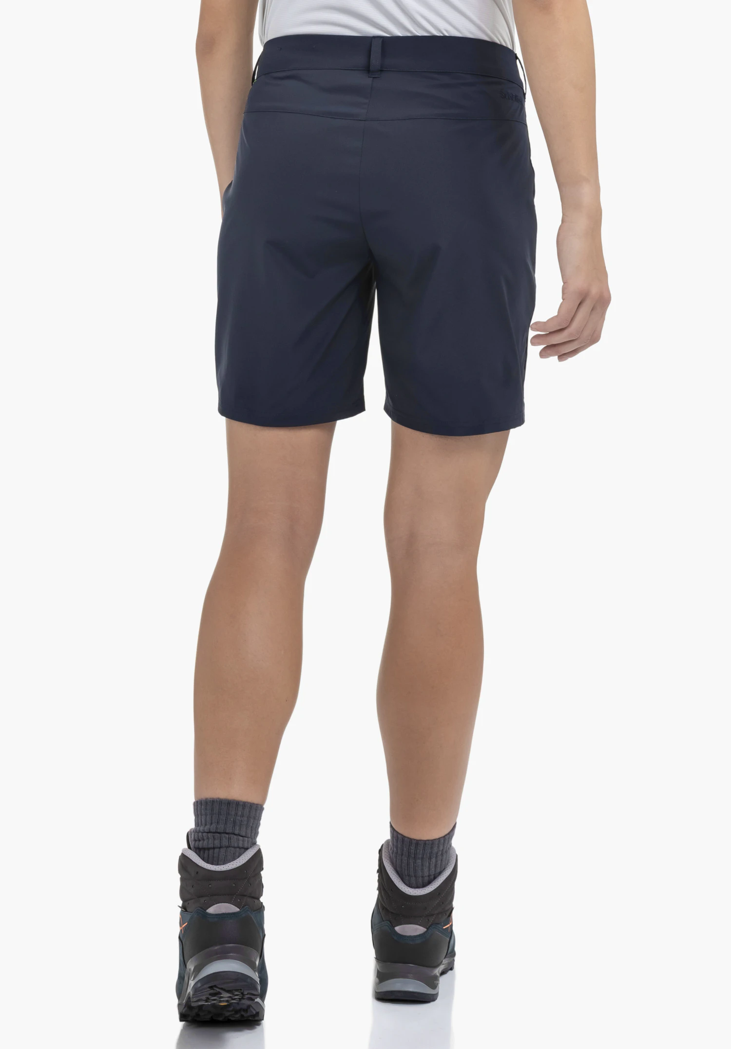 CIRC Shorts Style Smue WMN in der Farbe Blau, präsentiert von einem Model in der Rückenansicht. Zu sehen sind die Passform der kurzen Hose, die Gürtelschlaufen sowie das dezente Schöffel-Logo auf der rechten Rückseite. Das Model steht mit Wanderschuhen vor einem neutralen Hintergrund.