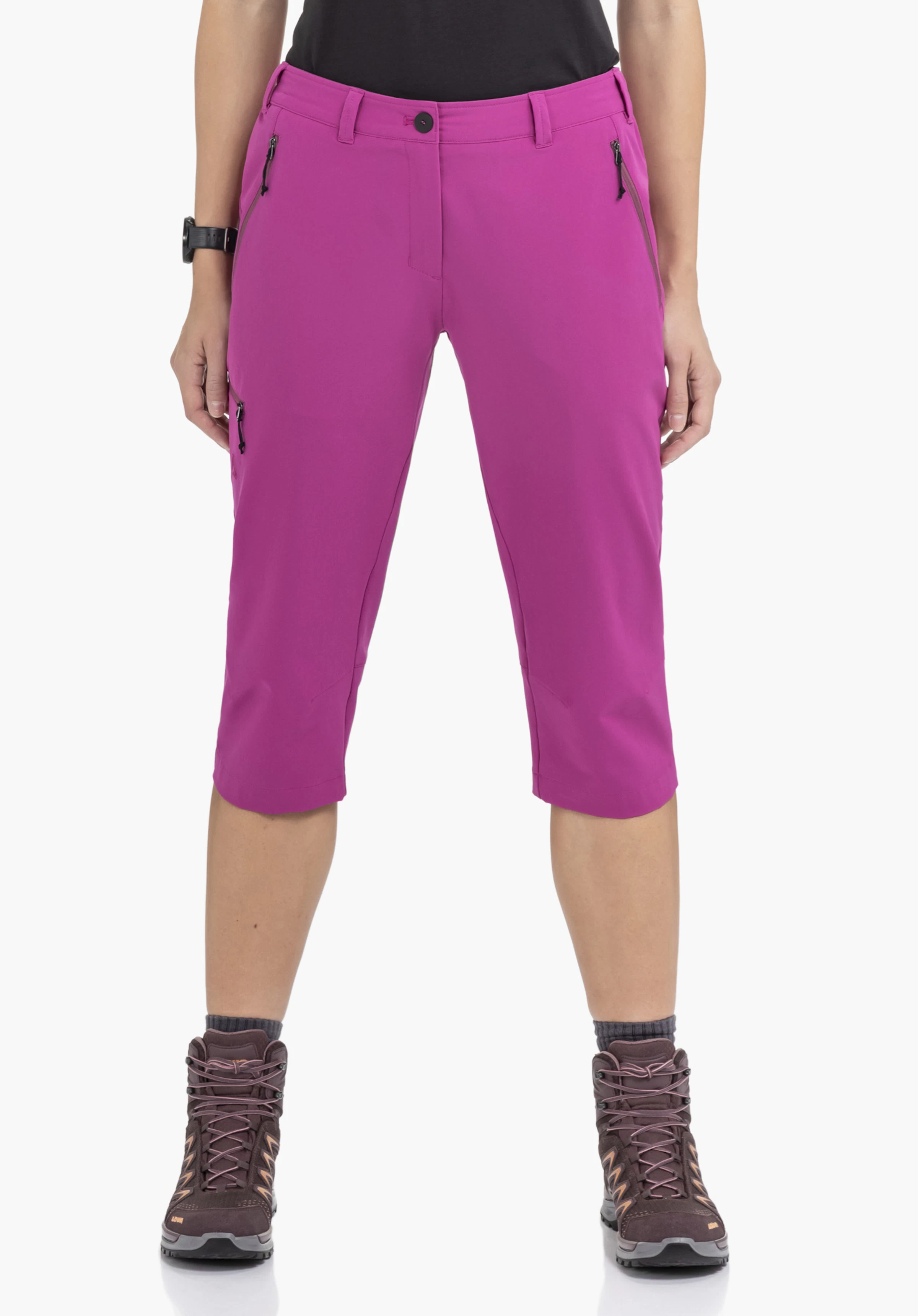 Pants Style Chavuma WMN an einem Model in der Vorderansicht. Man sieht die pinke 3/4-Hose mit Reißverschlusstaschen kombiniert mit dunklen Wanderschuhen vor einem neutralen Hintergrund.