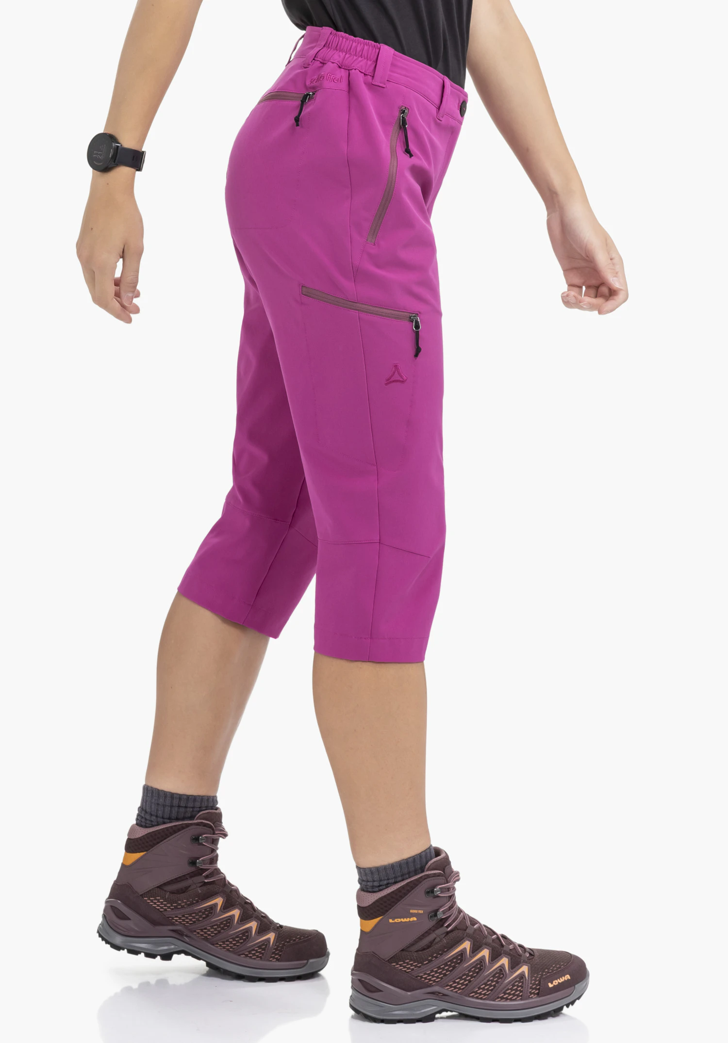 Pants Style Chavuma WMN wird von einem Model getragen, das seitlich in einer Schrittstellung steht. Die Hose in der Farbe Pink zeigt praktische Reißverschlusstaschen und das Schöffel-Logo auf dem Hosenbein vor einem neutralen Hintergrund.