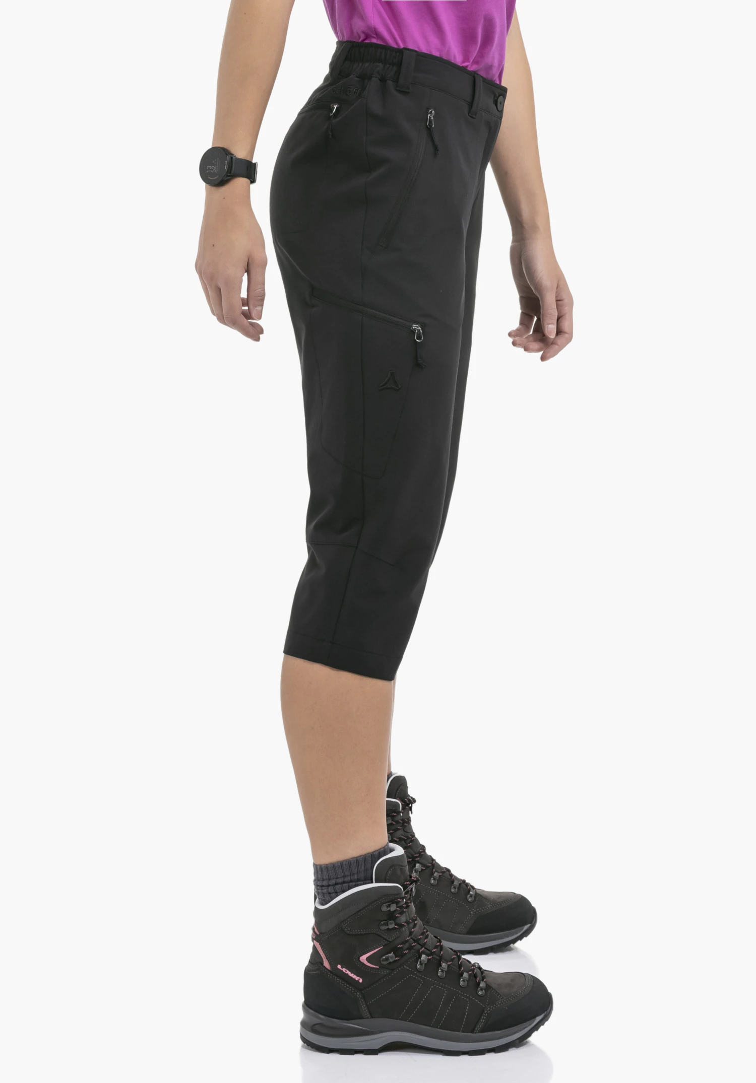 Pants Style Chavuma WMN an einem Model, das seitlich steht. Die schwarze 3/4-Hose zeigt eine Beintasche mit Reißverschluss sowie das Schöffel-Logo und wird vor einem neutralen Hintergrund präsentiert.