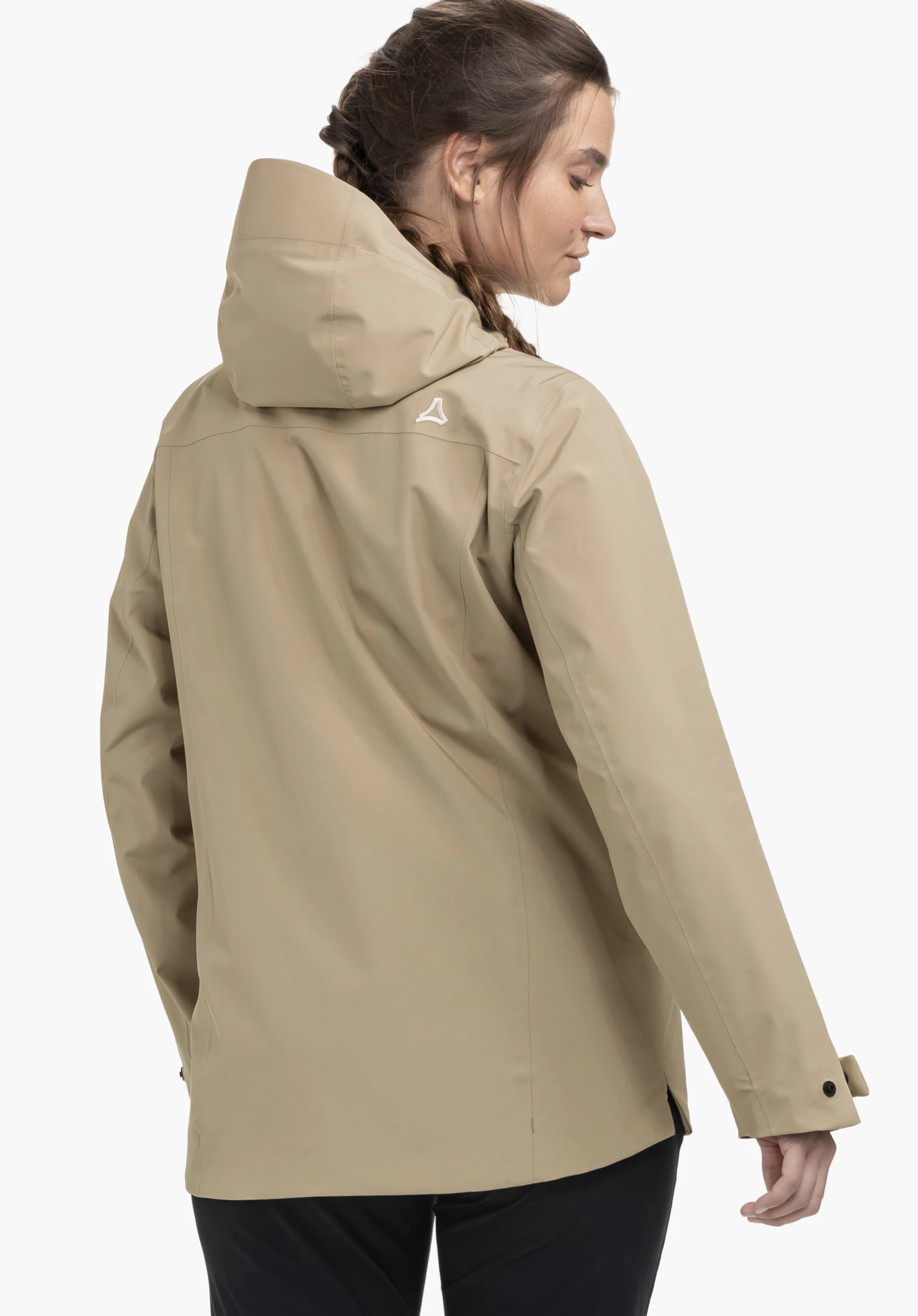 CIRC Jacket Style Smue WMN an einem Model in der Rückenansicht. Man sieht die beige Jacke mit Kapuze und dem Schöffel-Logo auf der rechten hinteren Schulterpartie. Das Model steht leicht seitlich gewandt vor einem neutralen Hintergrund.