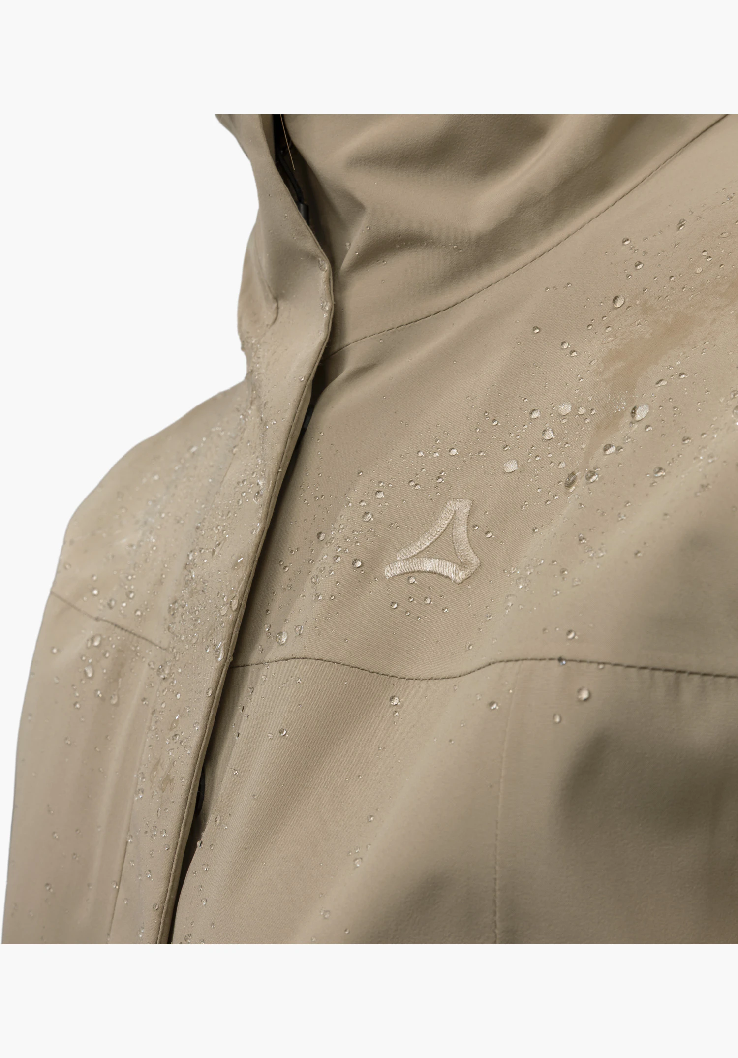 CIRC Jacket Style Smue WMN: wasserabweisender, beiger Stoff mit abperlenden Wassertropfen und aufgesticktem Schöffel-Logo. Nahaufnahme vor weißem/neutralem Hintergrund.