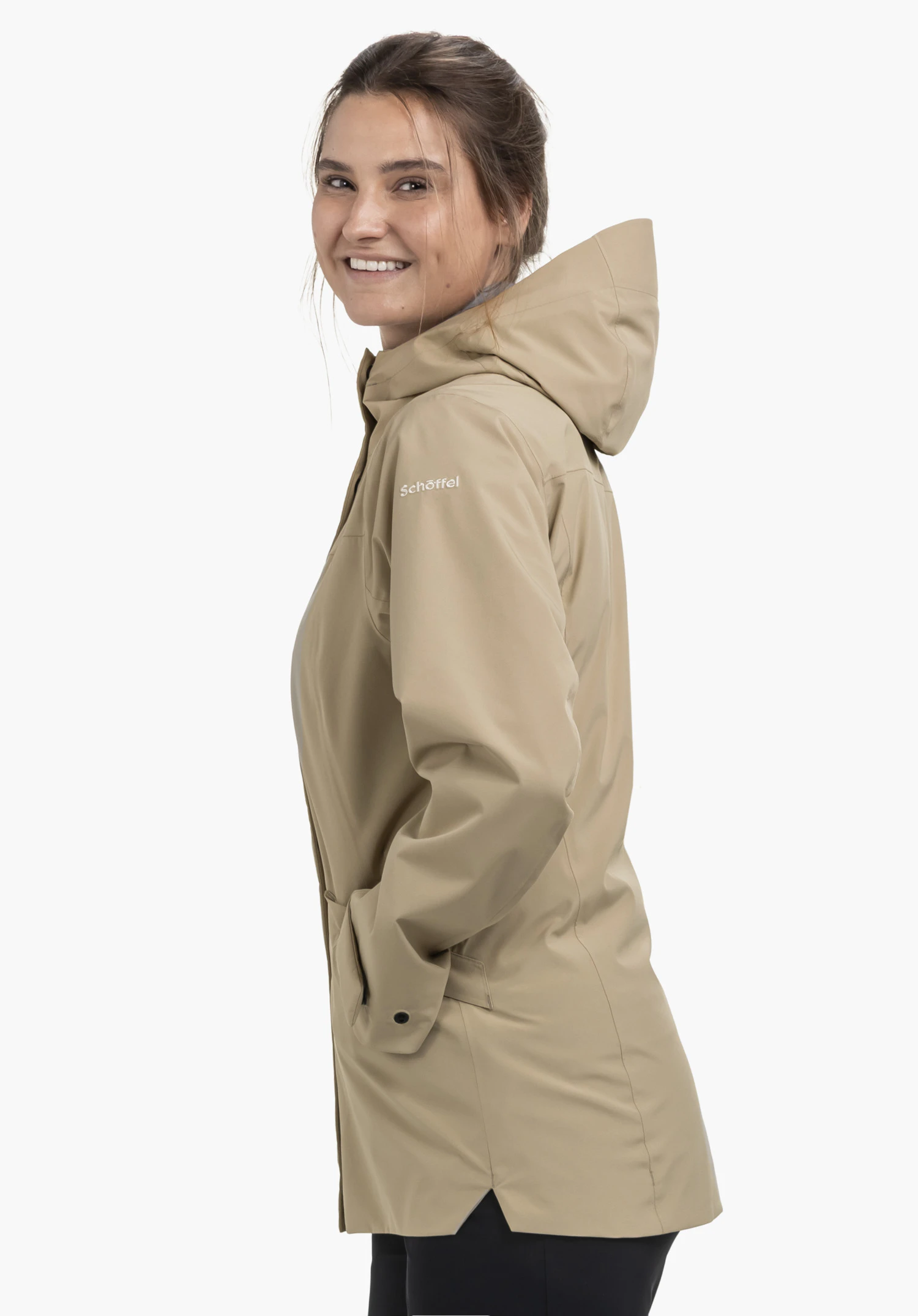 CIRC Jacket Style Smue WMN in Beige, getragen von einem Model. Das Model steht seitlich, hat die Hände in den Seitentaschen und lächelt in die Kamera. Das weiße Schöffel-Logo ist auf dem Oberarm gut sichtbar, präsentiert vor einem neutralen Hintergrund.
