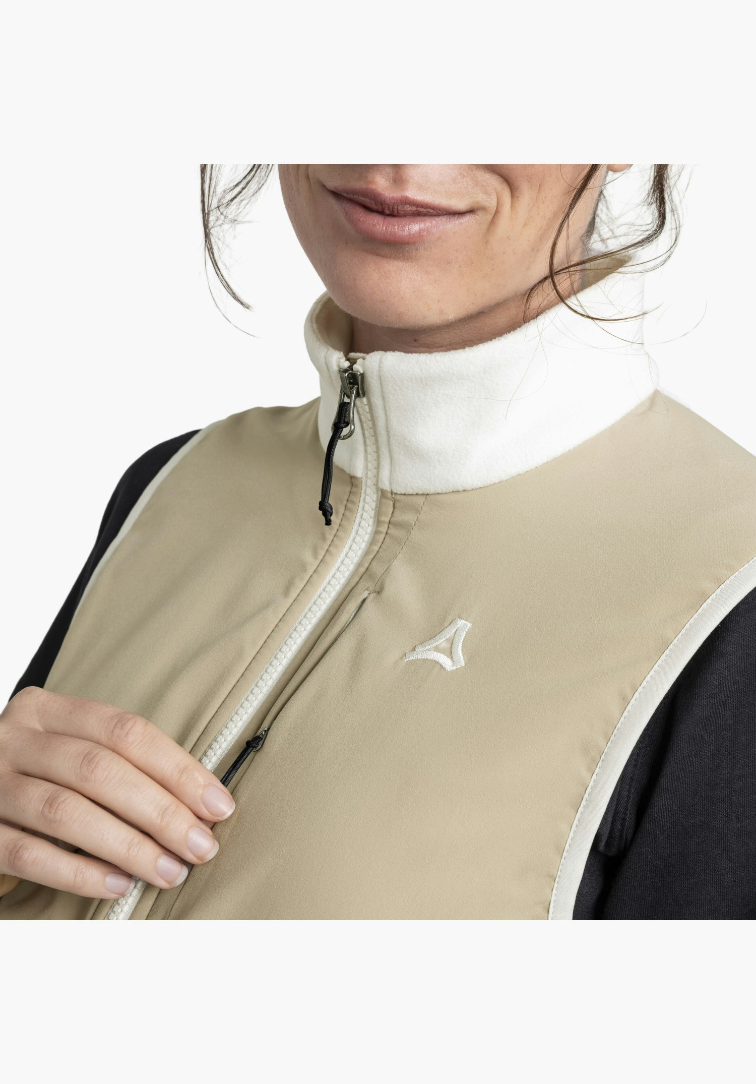 Fleece Vt Style Ash WMN präsentiert den hellen Fleece-Kragen, den Frontreißverschluss, das gestickte Schöffel-Logo auf dem glatten, naturfarbenen Stoff und eine verdeckte Brusttasche. Nahaufnahme vor weißem/neutralem Hintergrund.