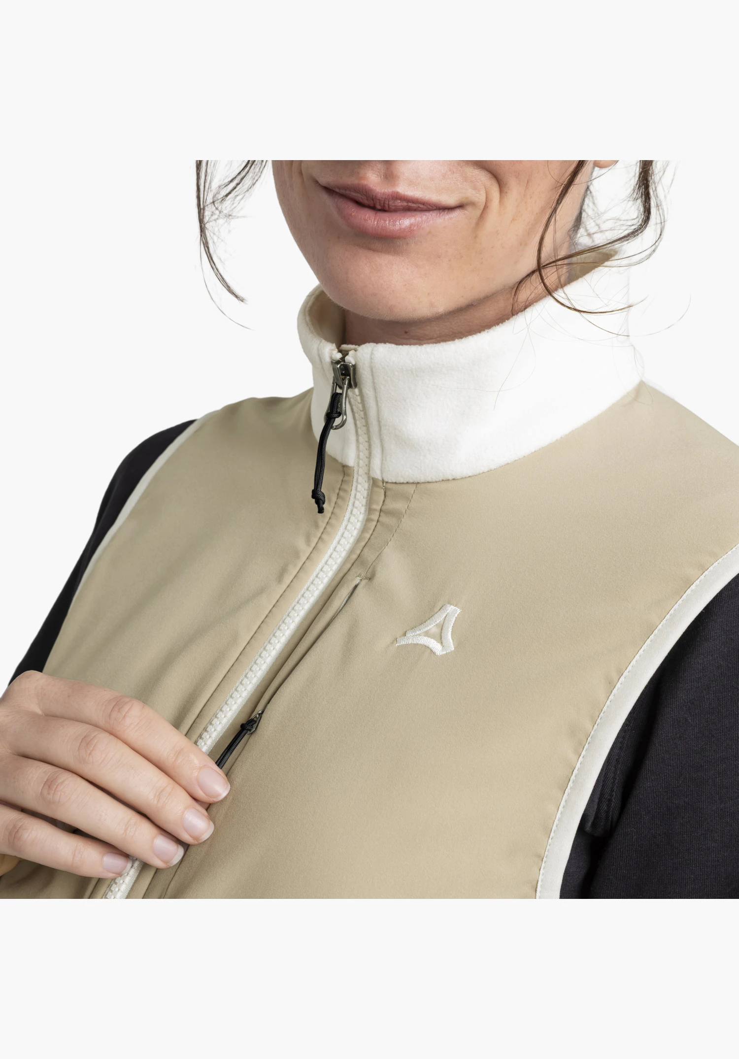 Fleece Vt Style Ash WMN toont de lichte fleece kraag, de ritssluiting aan de voorkant, het geborduurde Schöffel-Logo op de gladde, natuurkleurige stof en een verborgen borstzak. Close-up tegen een witte/neutrale achtergrond.