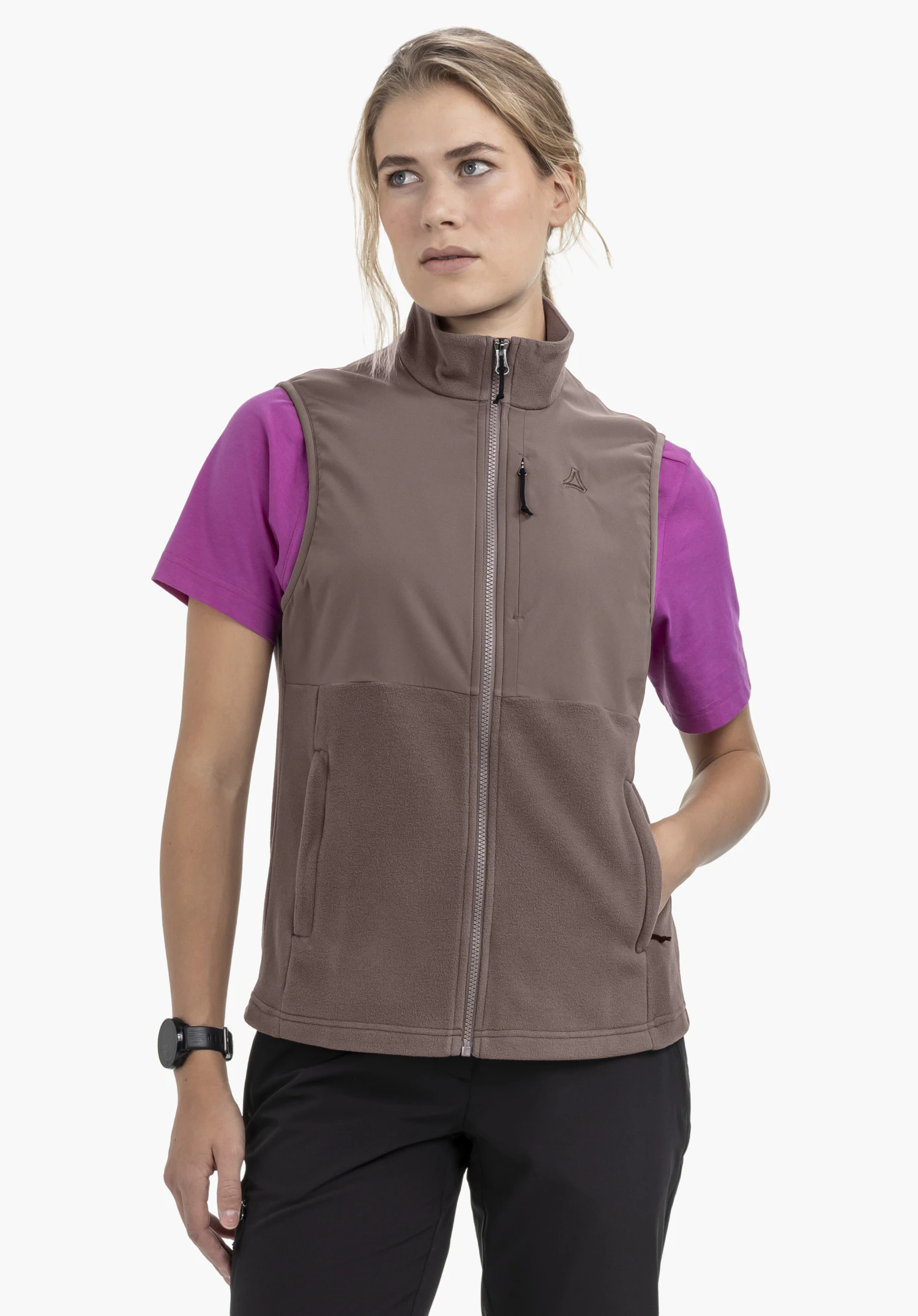 Fleece Vt Style Ash WMN on a model standing frontally and looking slightly to the side. She is wearing the brown gilet with a visible Schöffel logo on the left chest against a neutral background.