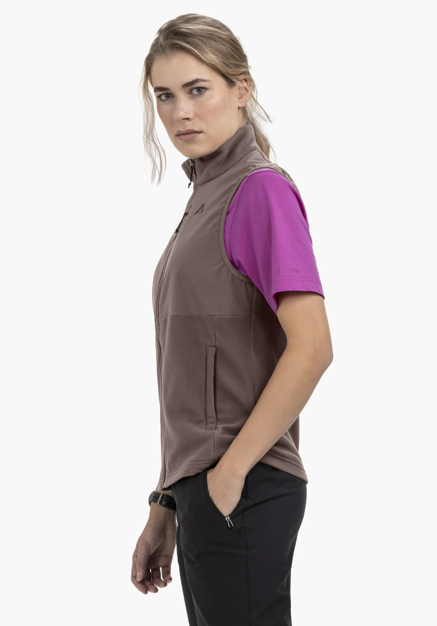 Fleece Vt Style Ash WMN. A model stands sideways wearing the brown gilet, with one hand resting casually in the side pocket. The Schöffel logo is visible on the chest, photographed against a neutral background.