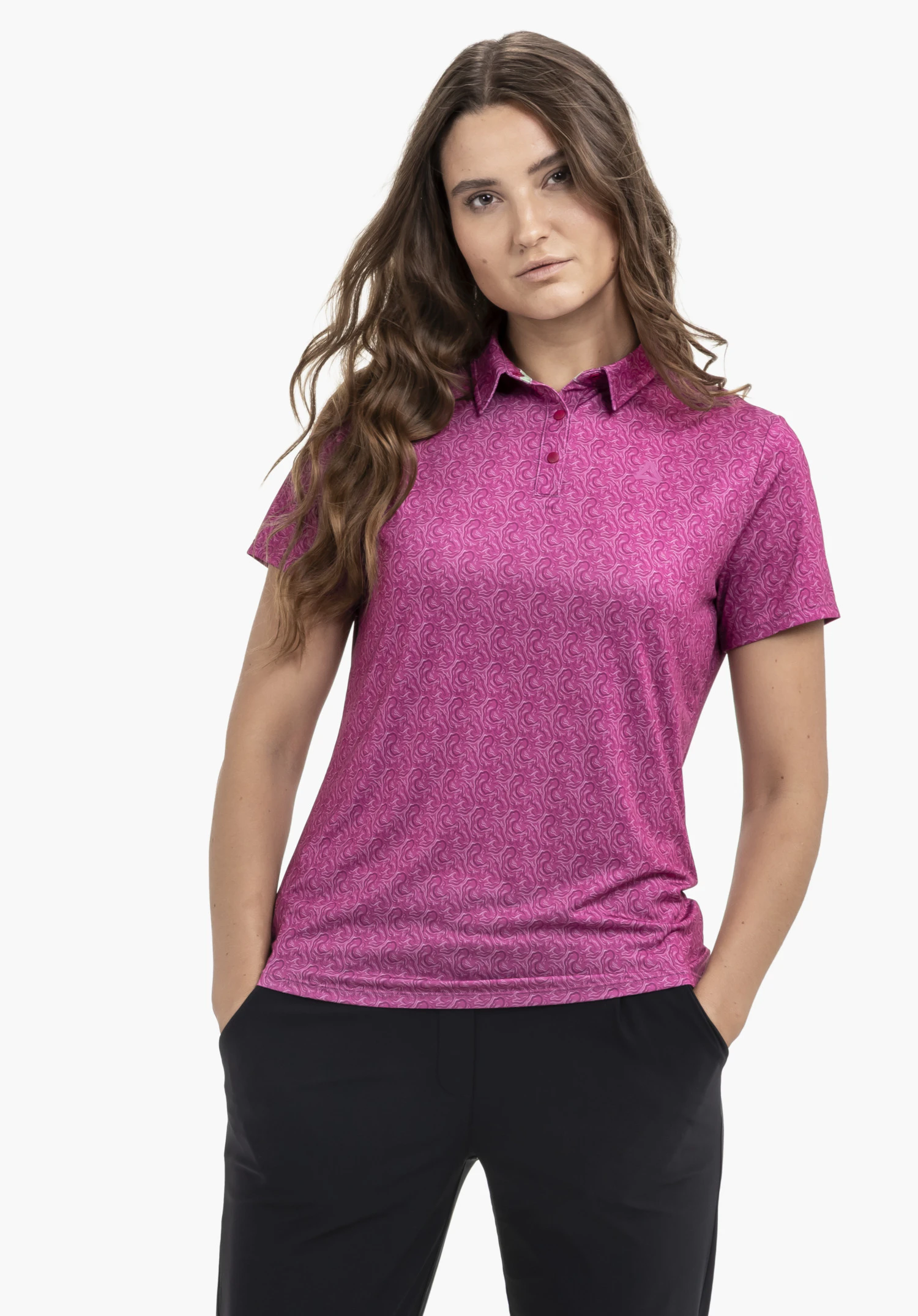 Polo Shirt Style Fraydo WMN in Pink mit durchgehendem Muster, getragen von einem Model. Das Model steht frontal mit den Händen in den Hosentaschen und auf der linken Brust ist das Schöffel-Logo dezent erkennbar, vor einem neutralen Hintergrund.