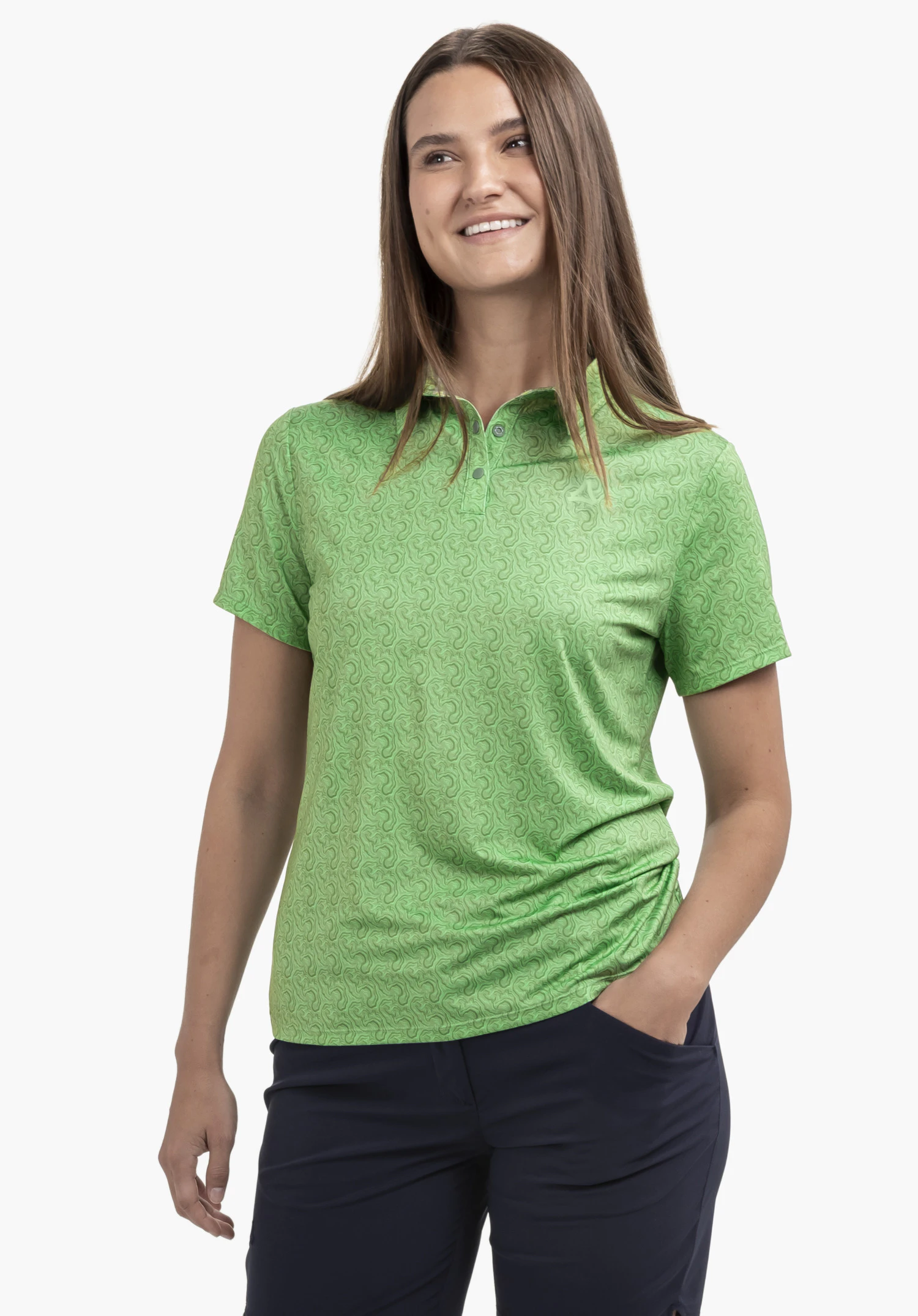 Polo Shirt Style Fraydo WMN in der Farbe Grün. Das Model steht frontal mit der linken Hand in der Hosentasche und präsentiert das gemusterte Kurzarm-Polo mit dezentem Schöffel-Logo auf der linken Brust vor einem neutralen Hintergrund.
