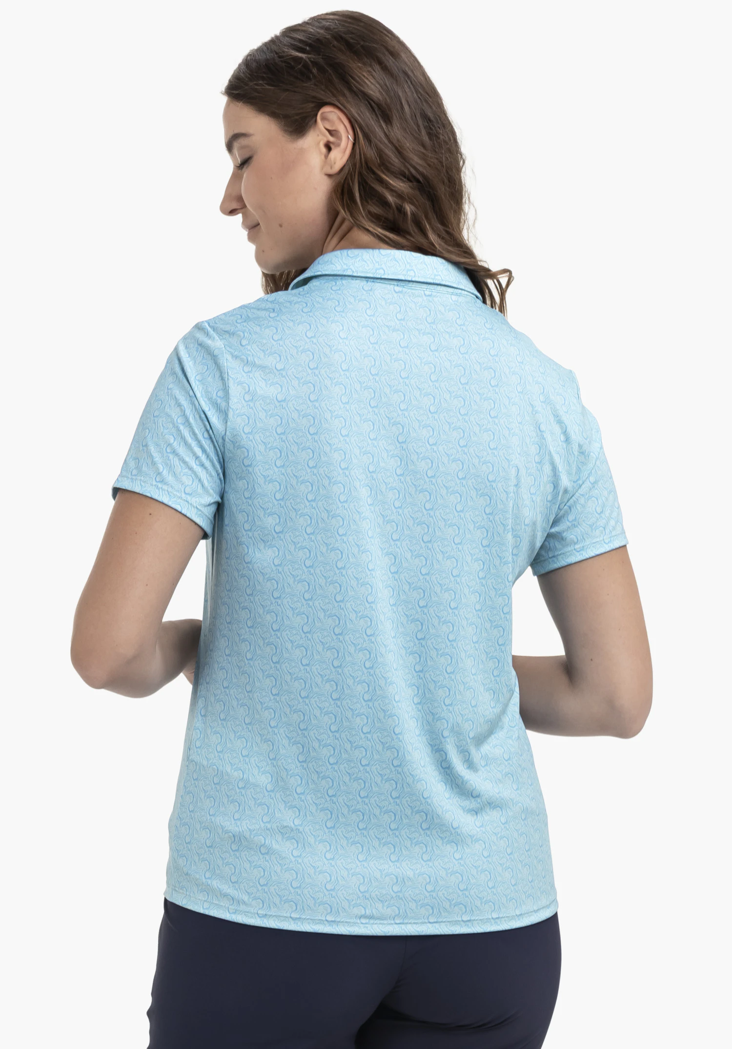 Polo Shirt Style Fraydo WMN en bleu présente le modèle de dos sur un fond neutre. L'accent est mis sur le tissu à motifs et le design classique du col qui souligne le look sportif.