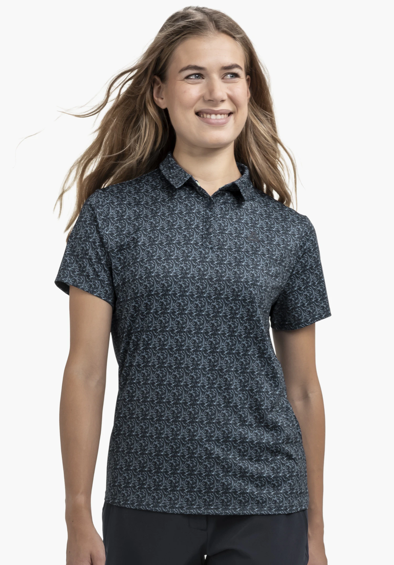 Polo Shirt Style Fraydo WMN an einem Model, das in Frontalansicht steht. Das blaue Kurzarm-Poloshirt zeigt ein feines Muster sowie das Schöffel-Logo auf der linken Brust und ist vor einem neutralen Hintergrund abgebildet.