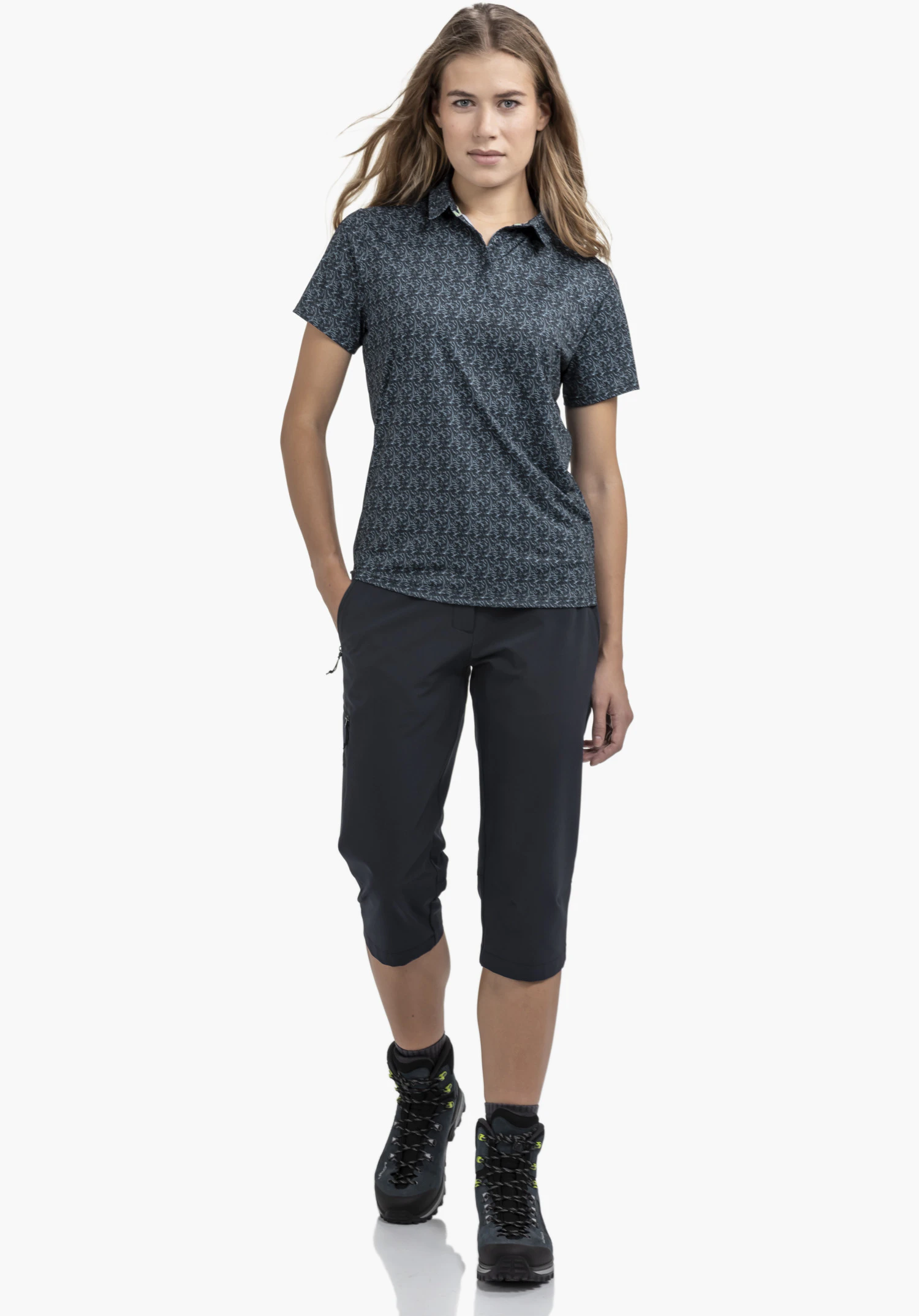 Polo Shirt Style Fraydo WMN zeigt den klassischen Kragen, die halboffene Knopfleiste, das blaue Material mit feinem Allover-Muster und das dezente Schöffel-Logo als Nahaufnahme vor weißem/neutralem Hintergrund.