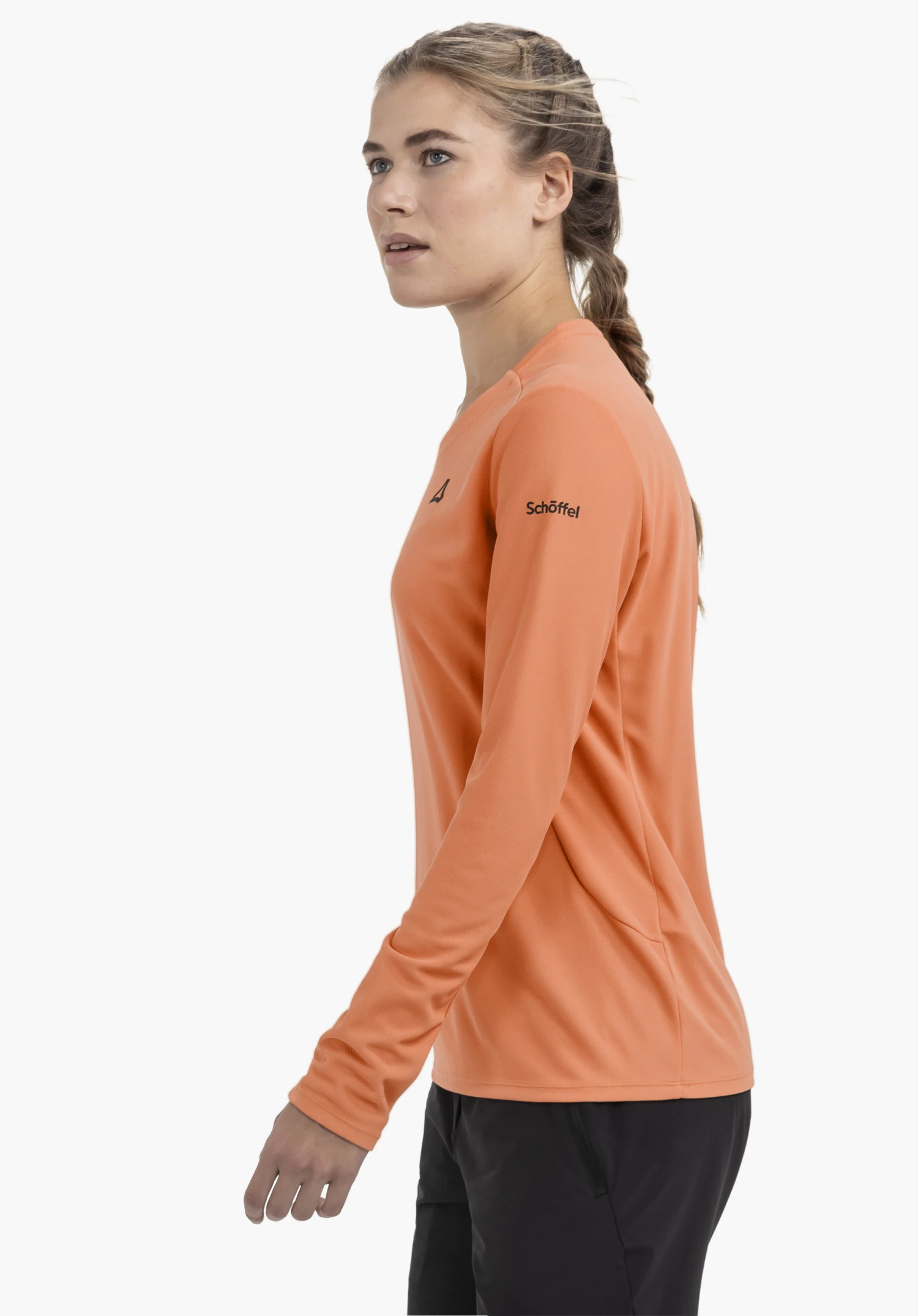 Longsleeve Style Enixa WMN en orange, porté par un mannequin qui se tient de profil et présente le logo Schöffel sur la manche, sur un fond neutre.