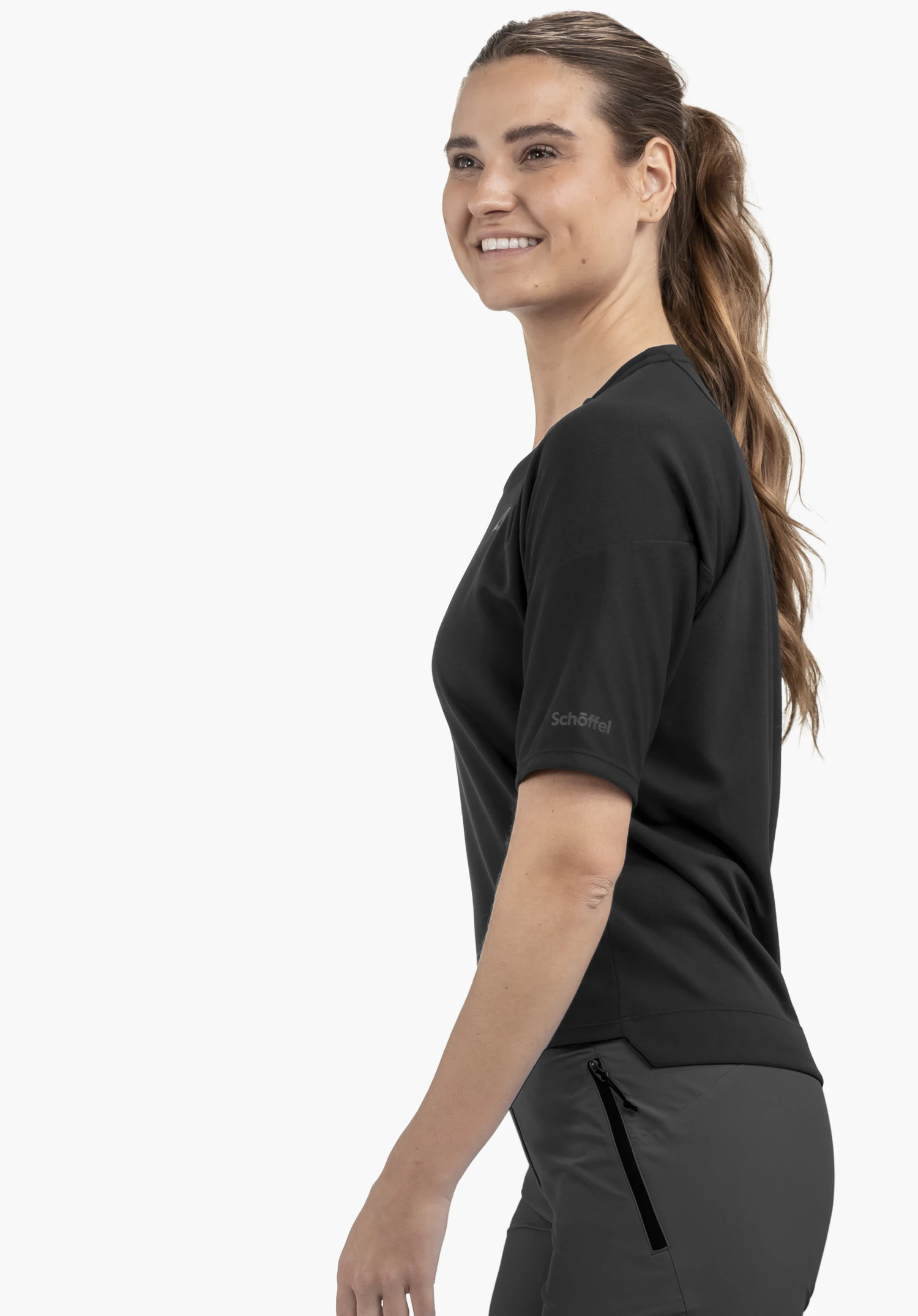 T Shirt Style Enixa WMN in black. The model is captured from a side profile against a neutral background, highlighting the garment with the subtle Schöffel logo visible on the sleeve.