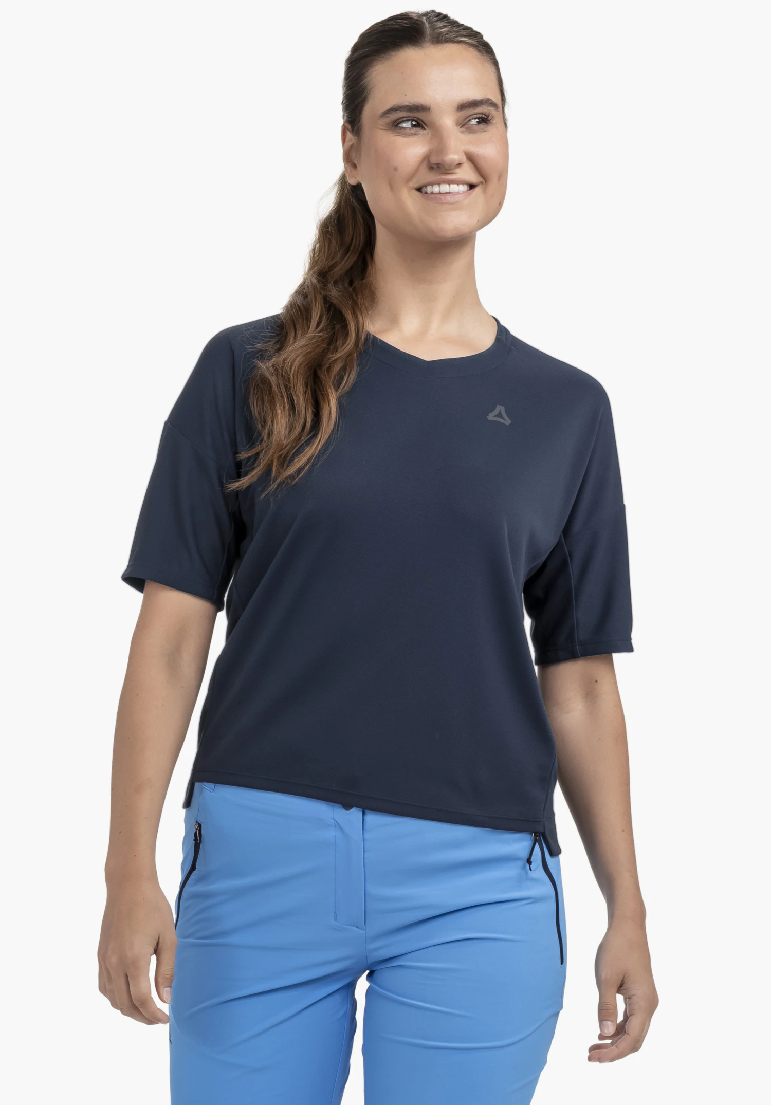 T Shirt Style Enixa WMN getragen von einem Model, das frontal steht. Das blaue T-Shirt zeigt das Schöffel-Logo auf der linken Brust und wird vor einem neutralen Hintergrund präsentiert.