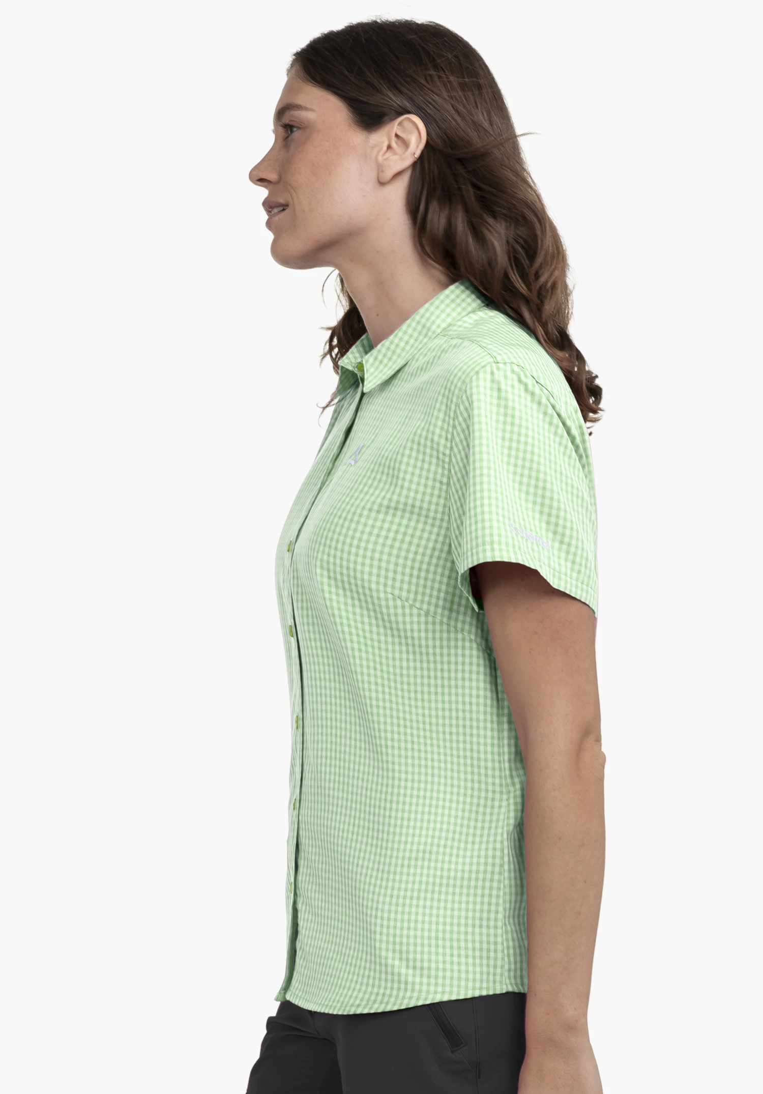 CIRC Blouse Style Dalfoss WMN sur un mannequin se tenant de profil. On y voit le chemisier à manches courtes à carreaux en vert avec le logo Schöffel visible sur la manche devant un fond neutre.