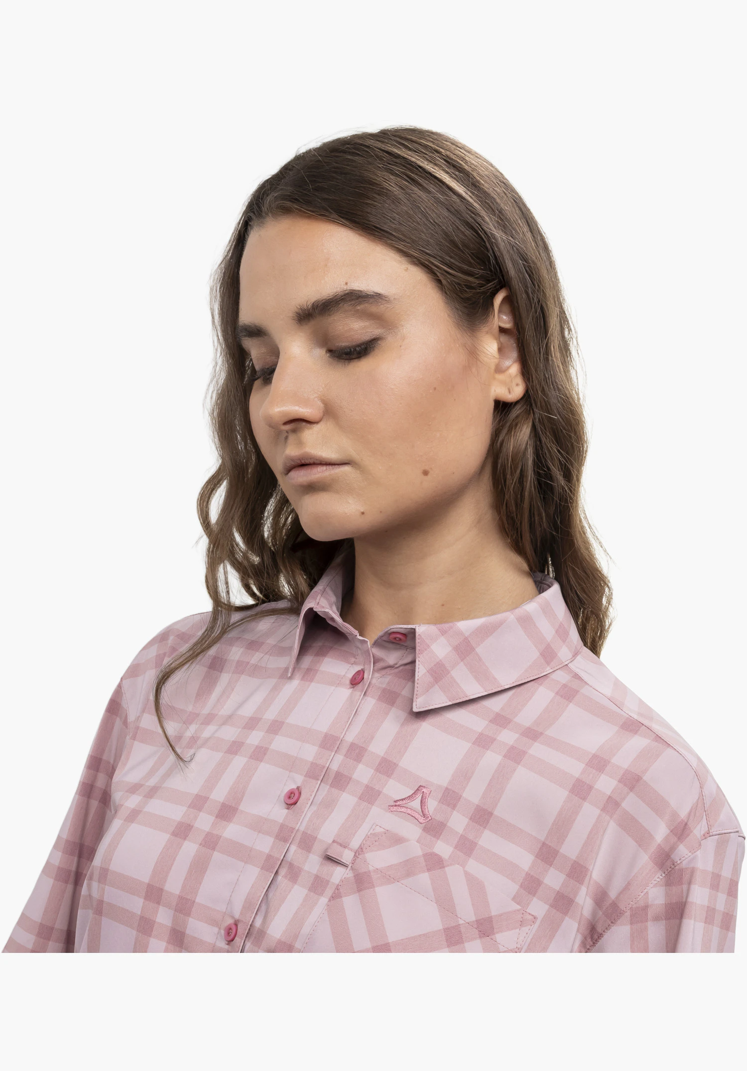 Blouse Style Fraris WMN. Un mannequin porte la chemise à carreaux rose en gros plan et regarde vers le bas. Le Schöffel-Logo est visible sur le côté gauche de la poitrine, posant devant un fond neutre.