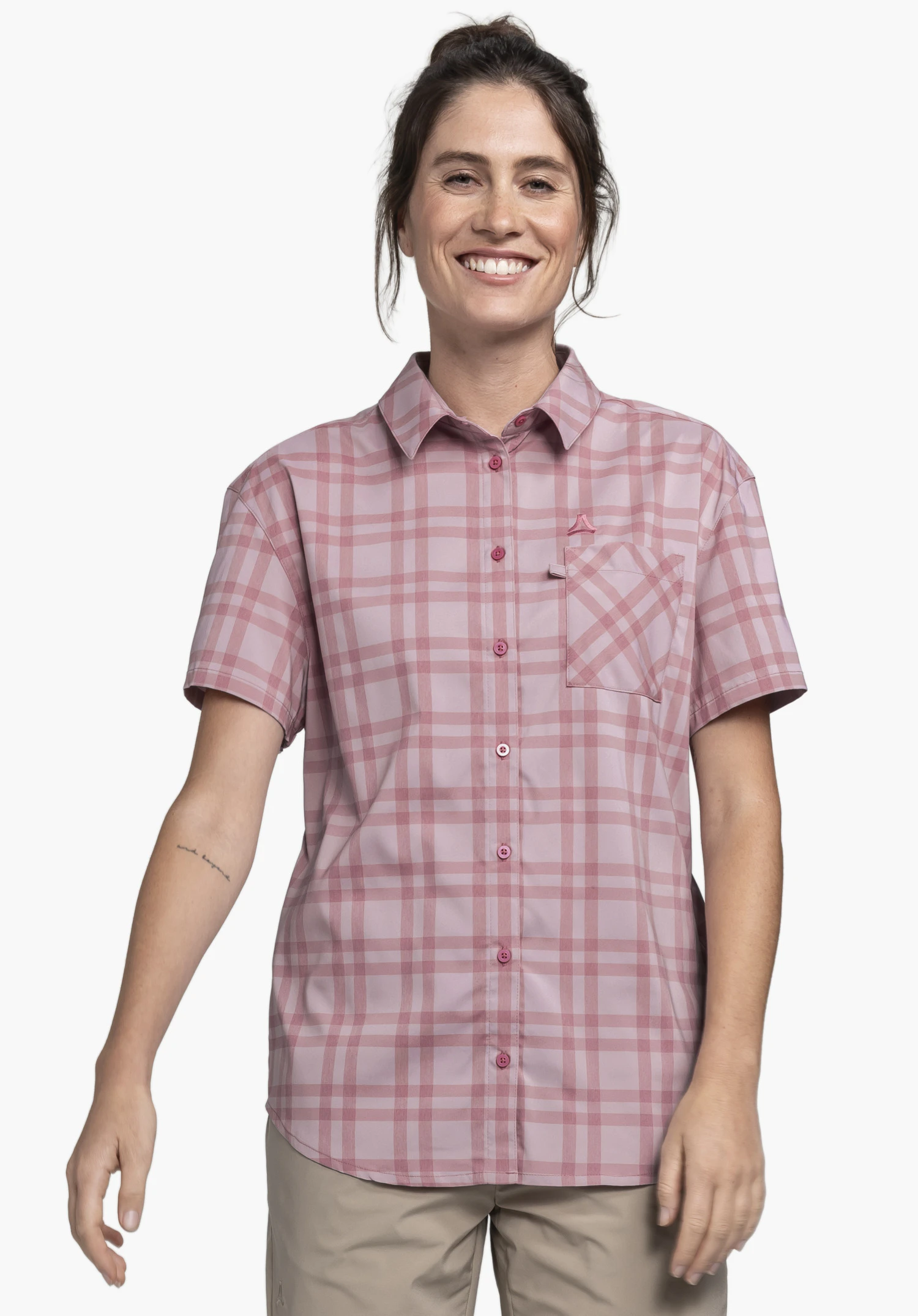 Blouse Style Frolya WMN wird von einem Model getragen, das frontal vor einem neutralen Hintergrund steht. Die rosa karierte Kurzarmbluse zeigt eine Brusttasche mit darüberliegendem Schöffel-Logo.