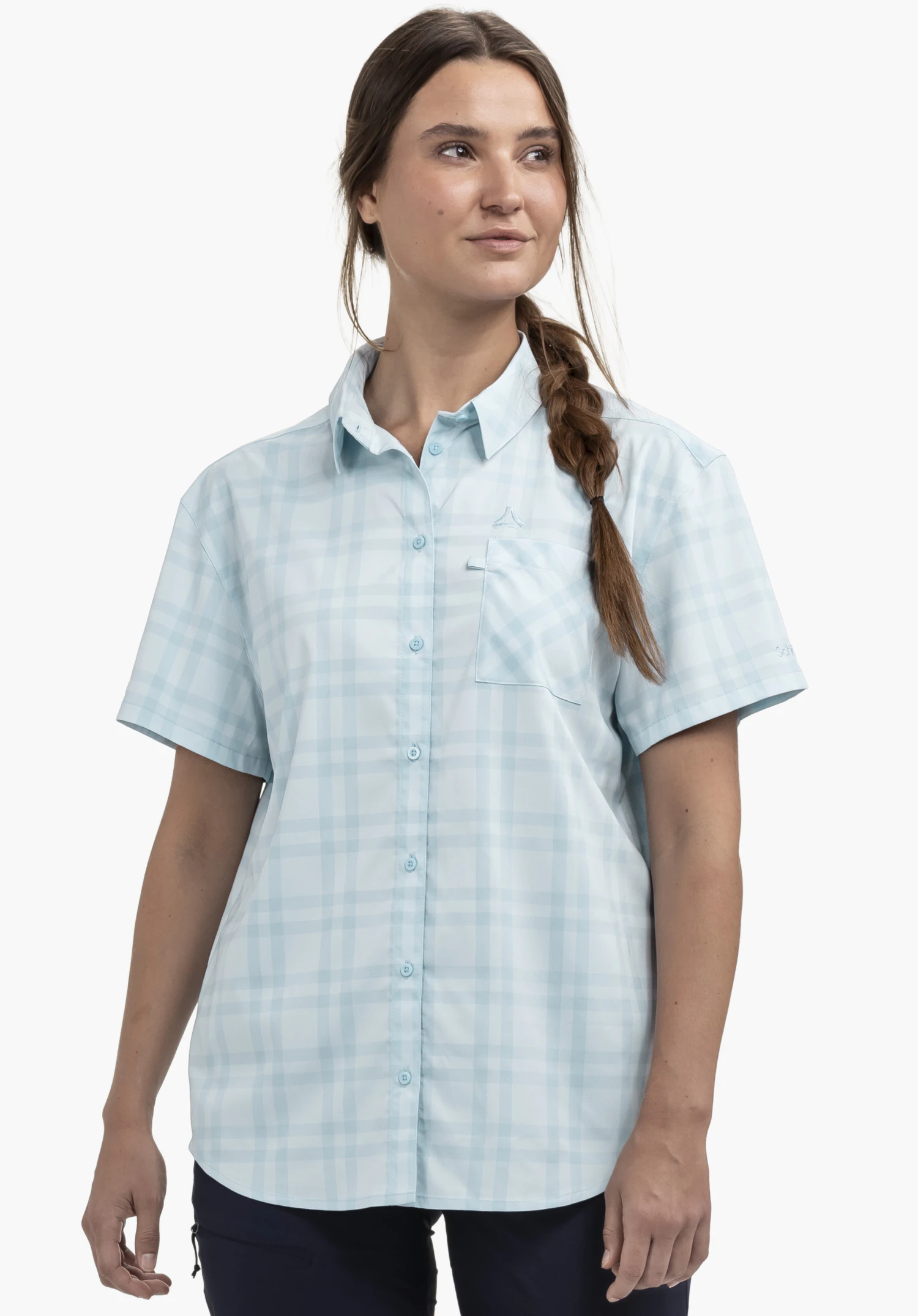 Blouse Style Frolya WMN sur un mannequin se tenant de face et regardant légèrement sur le côté. On y voit le chemisier bleu à manches courtes et à carreaux avec le logo Schöffel au-dessus de la poche poitrine devant un fond neutre.