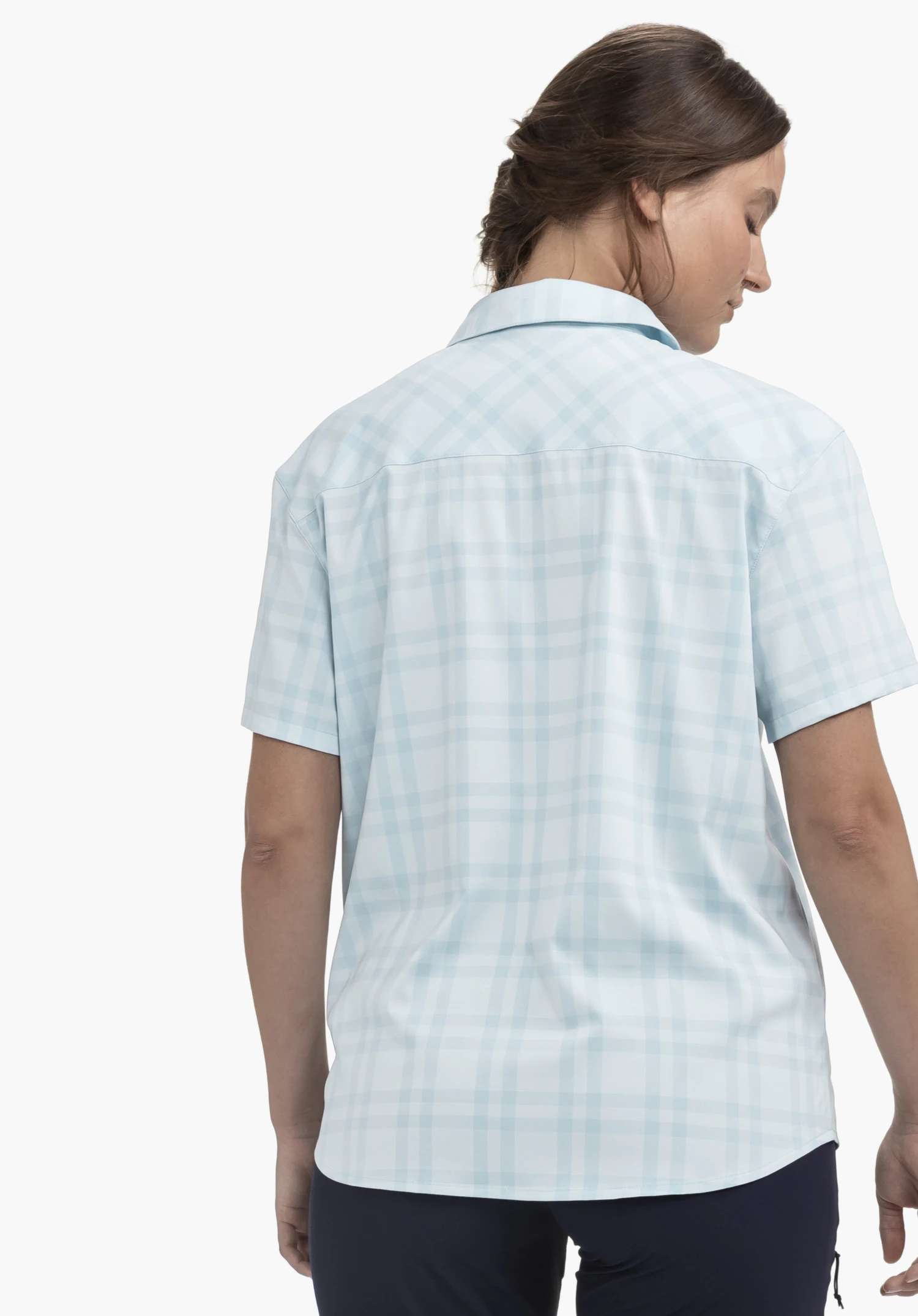Blouse Style Frolya WMN portée par un mannequin vu de dos. Le chemisier à manches courtes et à carreaux en bleu est associé à un pantalon foncé, alors que le mannequin se tient devant un fond neutre.