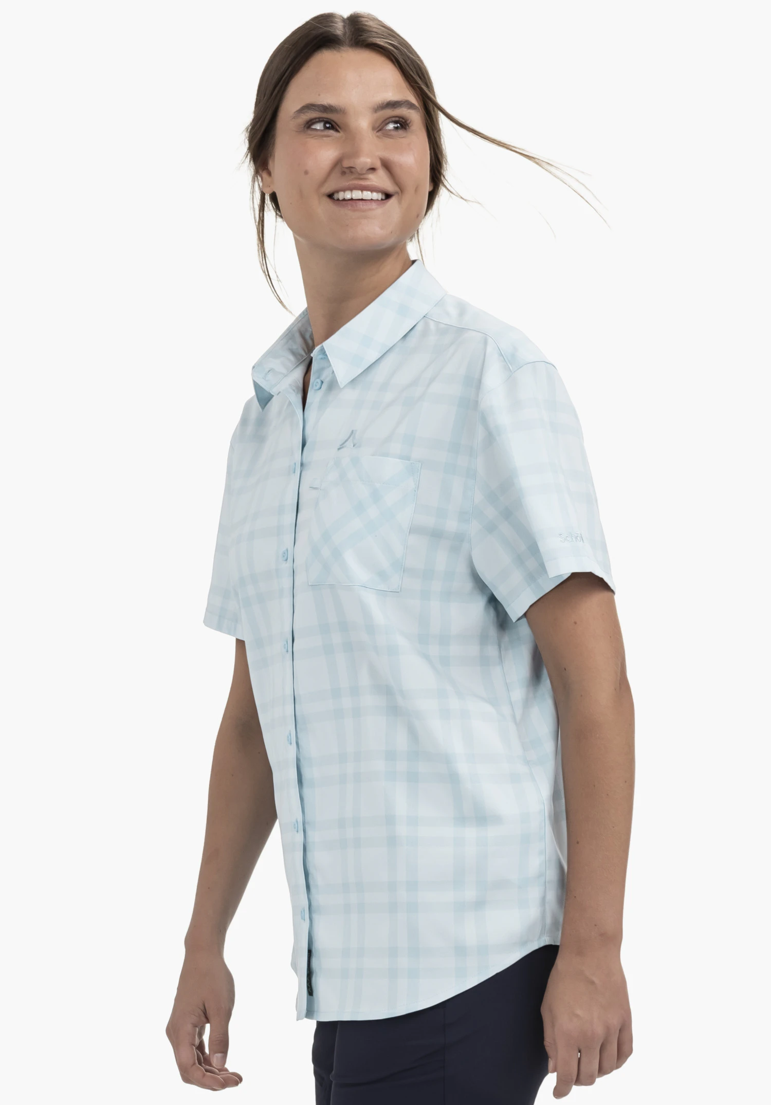 Blouse Style Frolya WMN. Un mannequin se tient de profil et porte le chemisier à manches courtes à carreaux bleus doté d'une poche poitrine. Le logo Schöffel est visible au-dessus de la poche poitrine et sur la manche gauche, présenté sur un fond neutre.