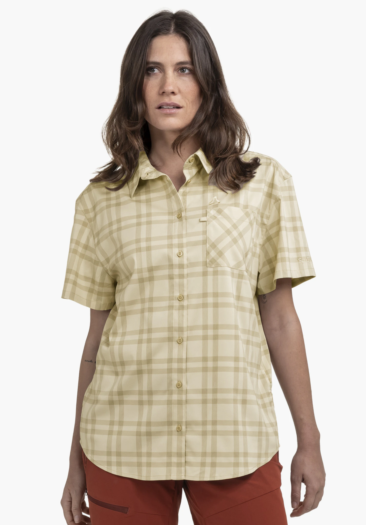 Blouse Style Frolya WMN an einem Model, das frontal steht. Man sieht die kurzärmlige, beige karierte Bluse mit durchgehender Knopfleiste, einer Brusttasche mit dezentem Schöffel-Logo und einem weiteren Logo-Schriftzug am linken Ärmel, fotografiert vor einem neutralen Hintergrund.