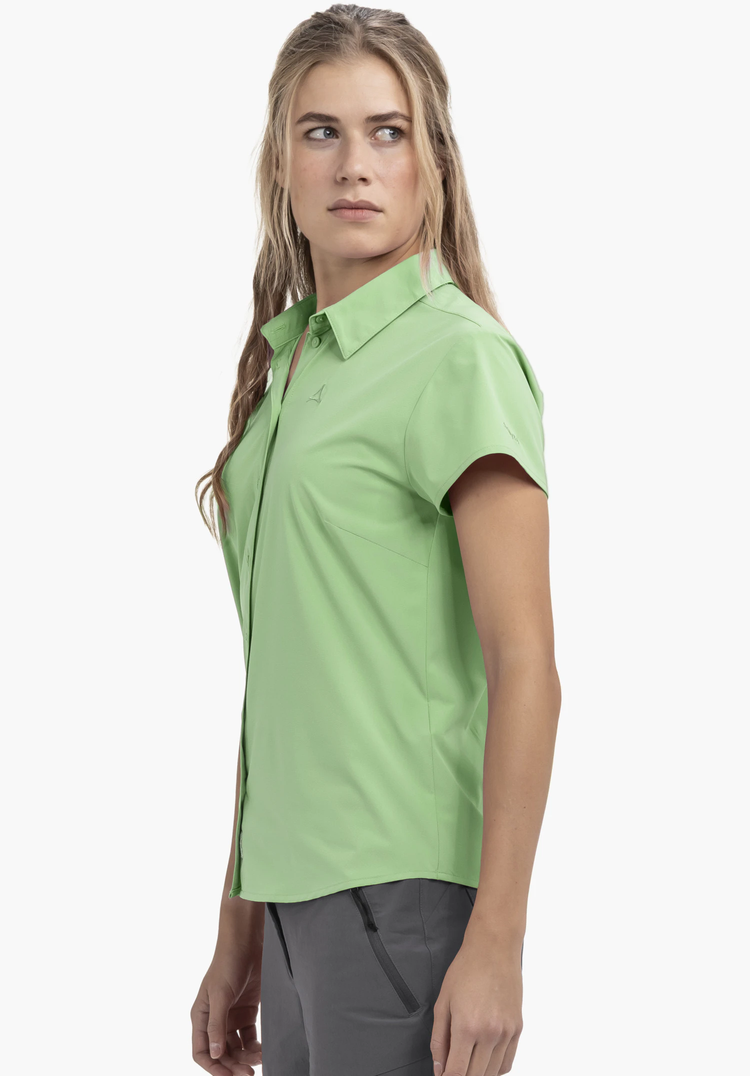 Blouse Style Dooser WMN en vert : La blouse est présentée sur un mannequin en vue latérale sur un fond neutre. Le logo Schöffel discret est visible au niveau de la poitrine et souligne le look haut de gamme.