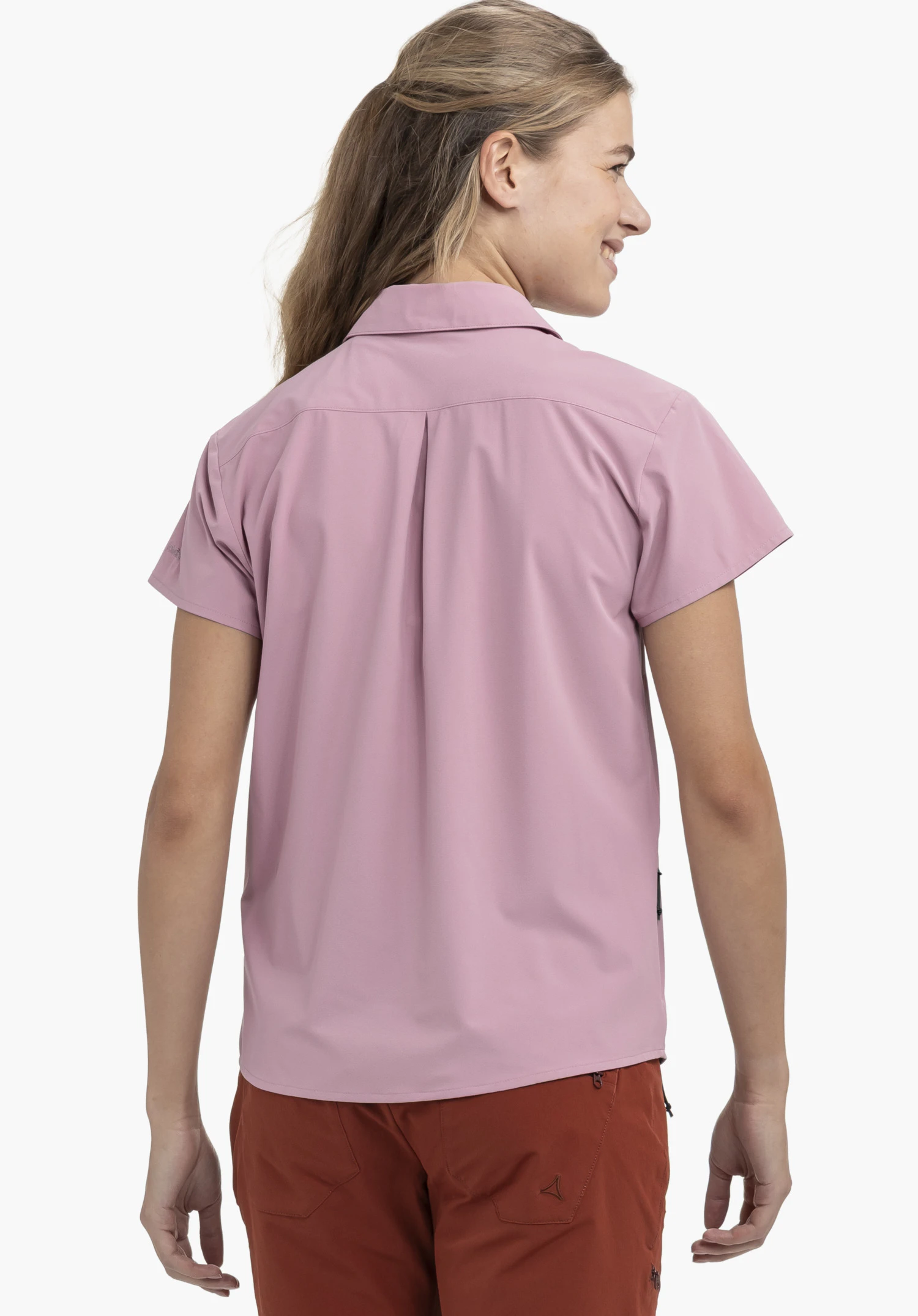 Blouse Style Dooser WMN in roze. Je ziet een model in een achteraanzicht die de blouse met korte mouwen draagt, voorzien van een centrale rugplooi en een klein Schöffel-Logo op de linkermouw. Het model staat voor een neutrale achtergrond.
