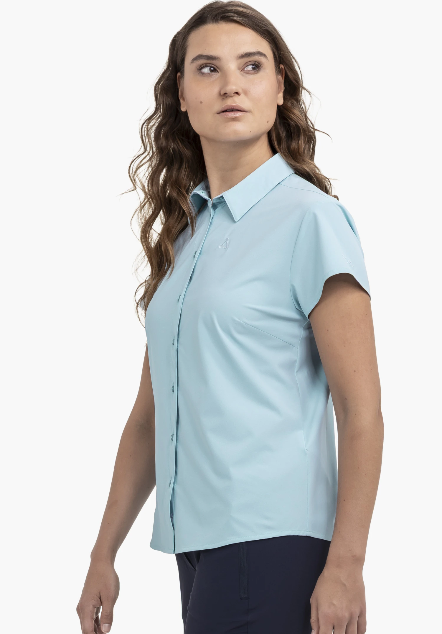 Blouse Style Dooser WMN in Blau. Das Model steht seitlich vor einem neutralen Hintergrund und präsentiert das Modell, das dezent mit dem Schöffel-Logo auf der Brust versehen ist.